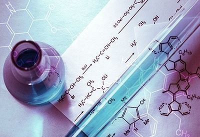 A chemical formula is written on a piece of paper next to a beaker.