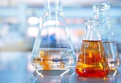 Three beakers filled with liquid are sitting on a table in a laboratory.