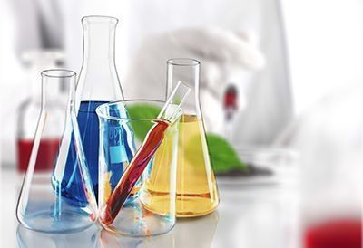 A group of beakers filled with different colored liquids on a table.