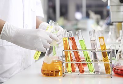 A scientist is pouring liquid into test tubes in a laboratory.