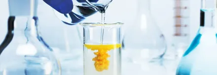 A person is pouring liquid into a test tube in a laboratory.