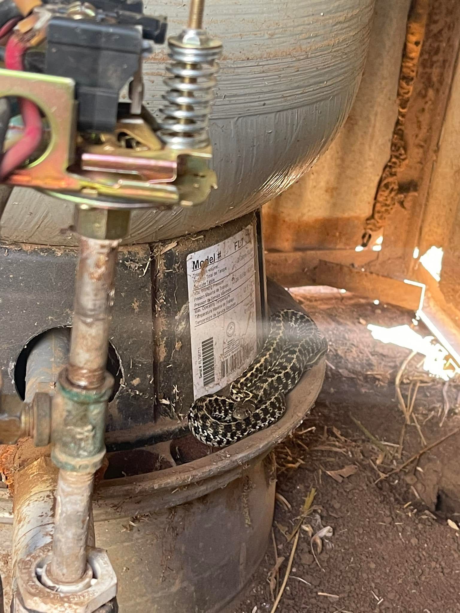 Close-up of a lawn mower deck with a spring and metal linkage under a tire.