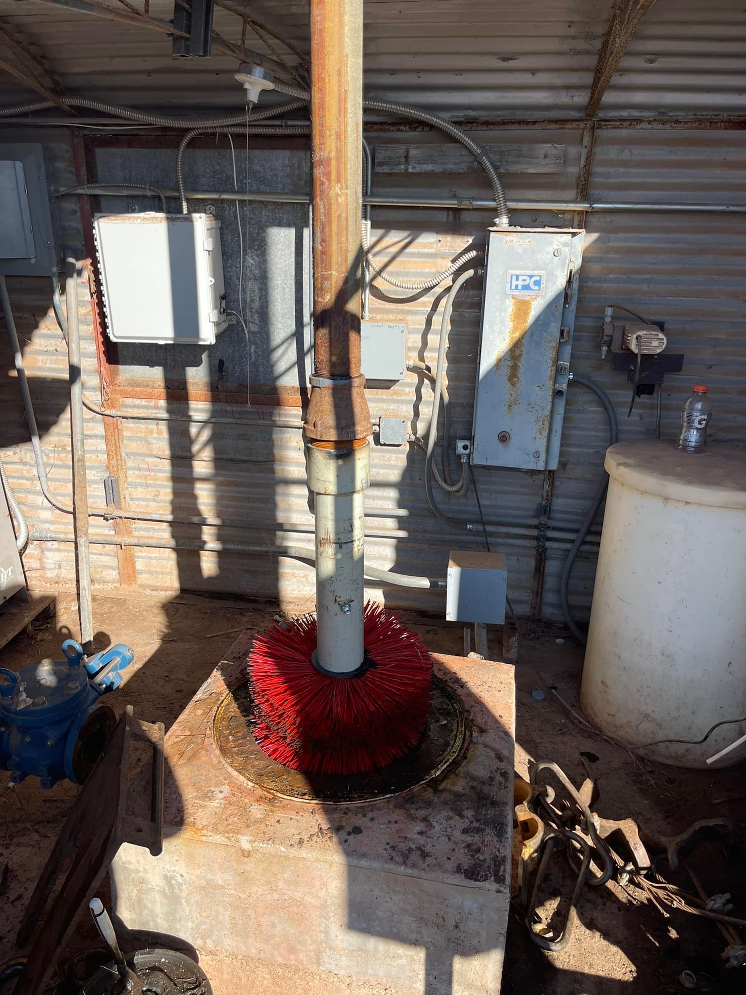 Utility pole base with red protective material beside electrical equipment under a covered structure