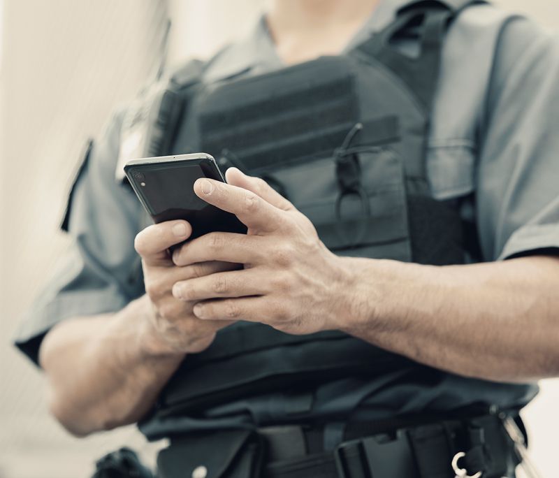 A police officer is holding a cell phone in his hands