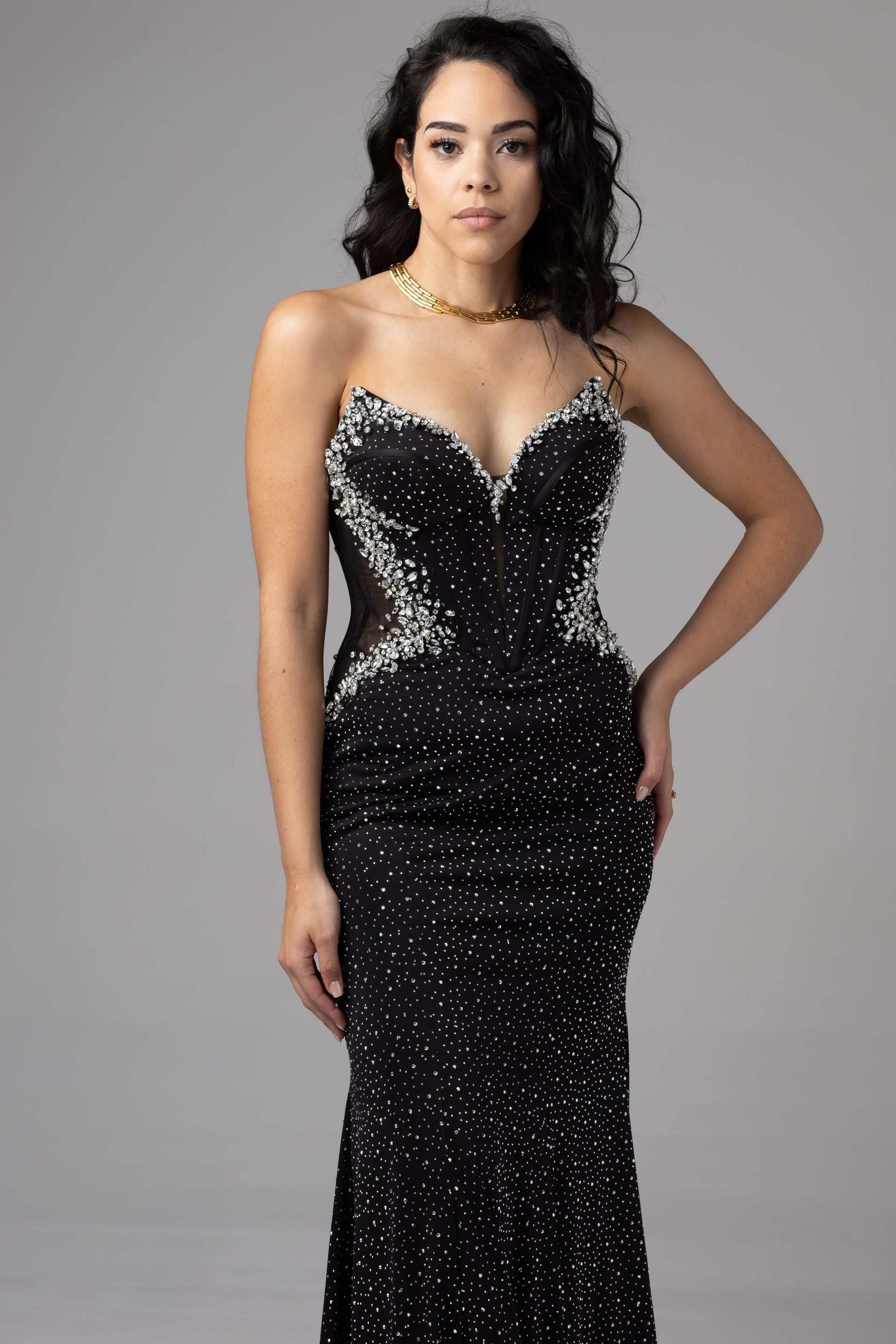 Woman in a black sequined evening gown standing against a gray backdrop