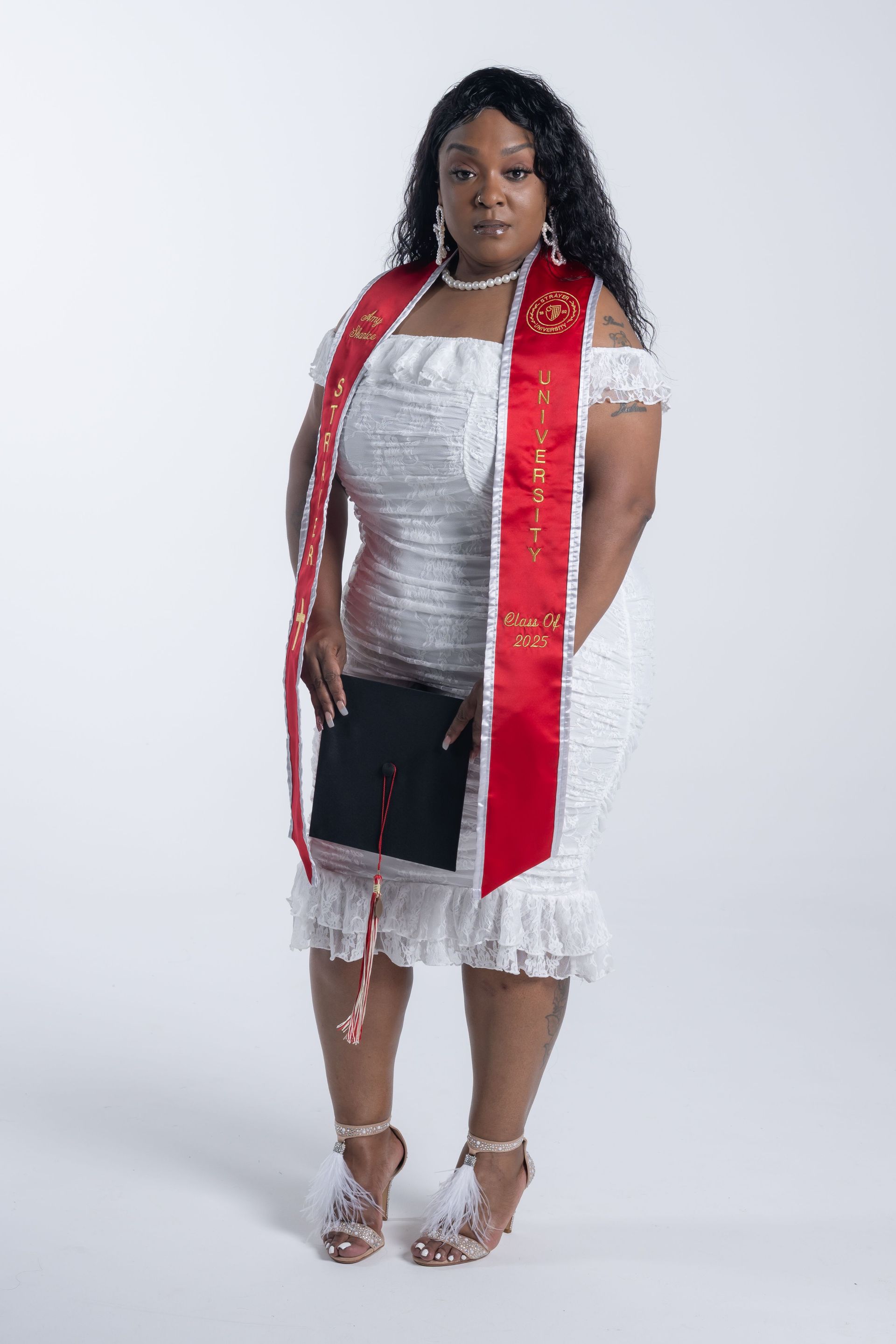 Person posing in a silver dress, red scarf, and silver heels against a plain studio backdrop.