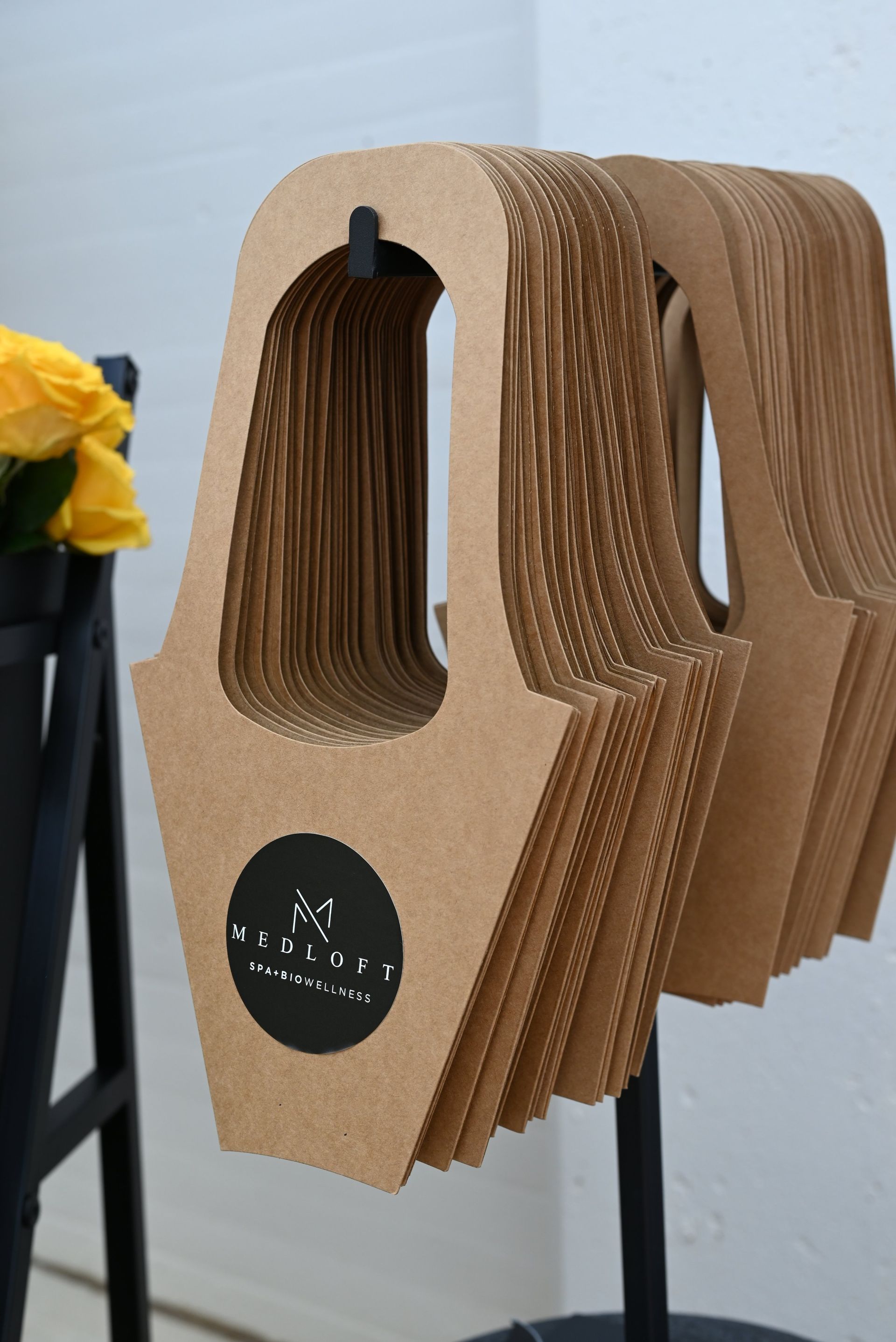 Stack of brown corrugated cardboard takeout carriers with black circular labels on a table