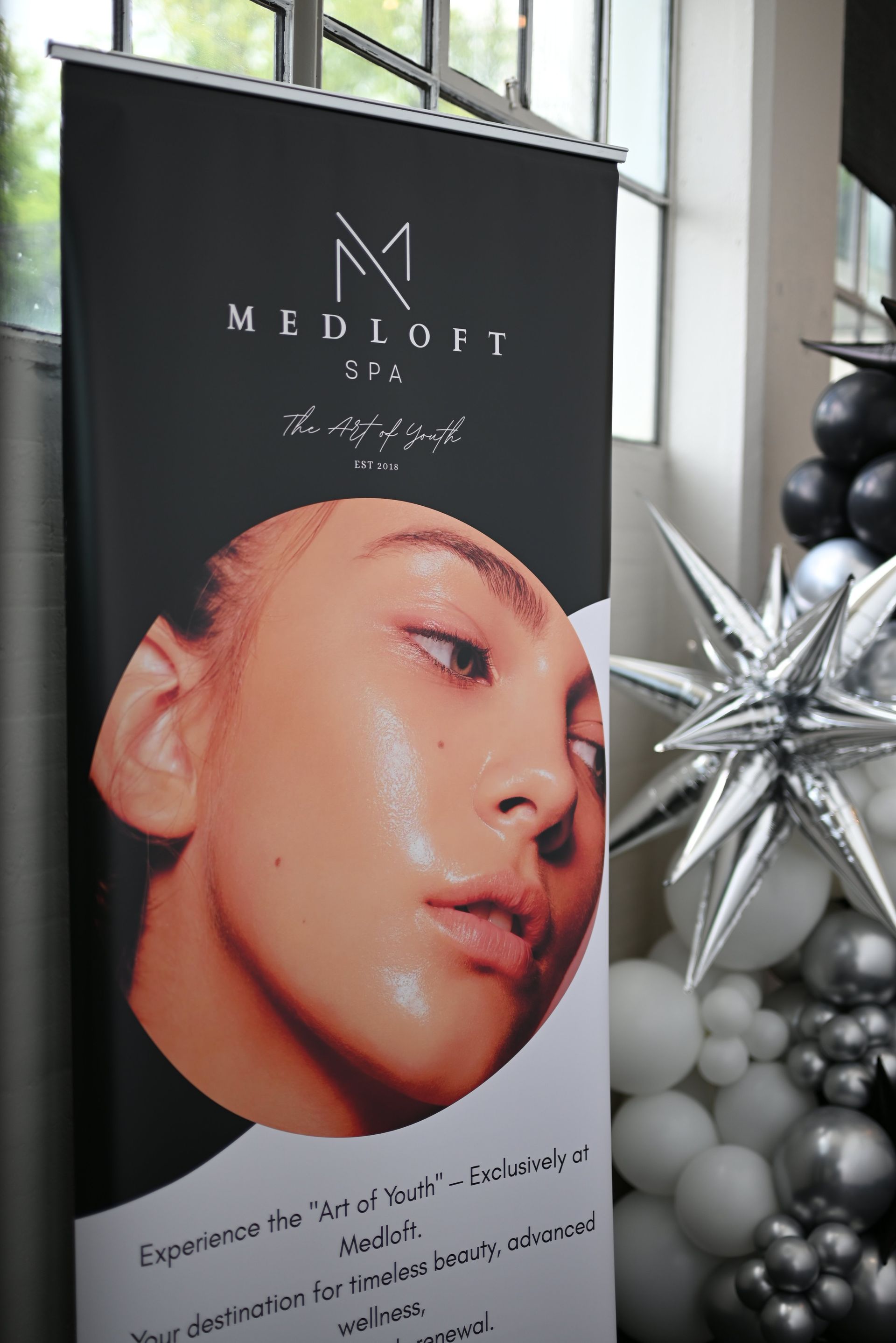 Beauty product poster with a close-up face and silver holiday decor beside it