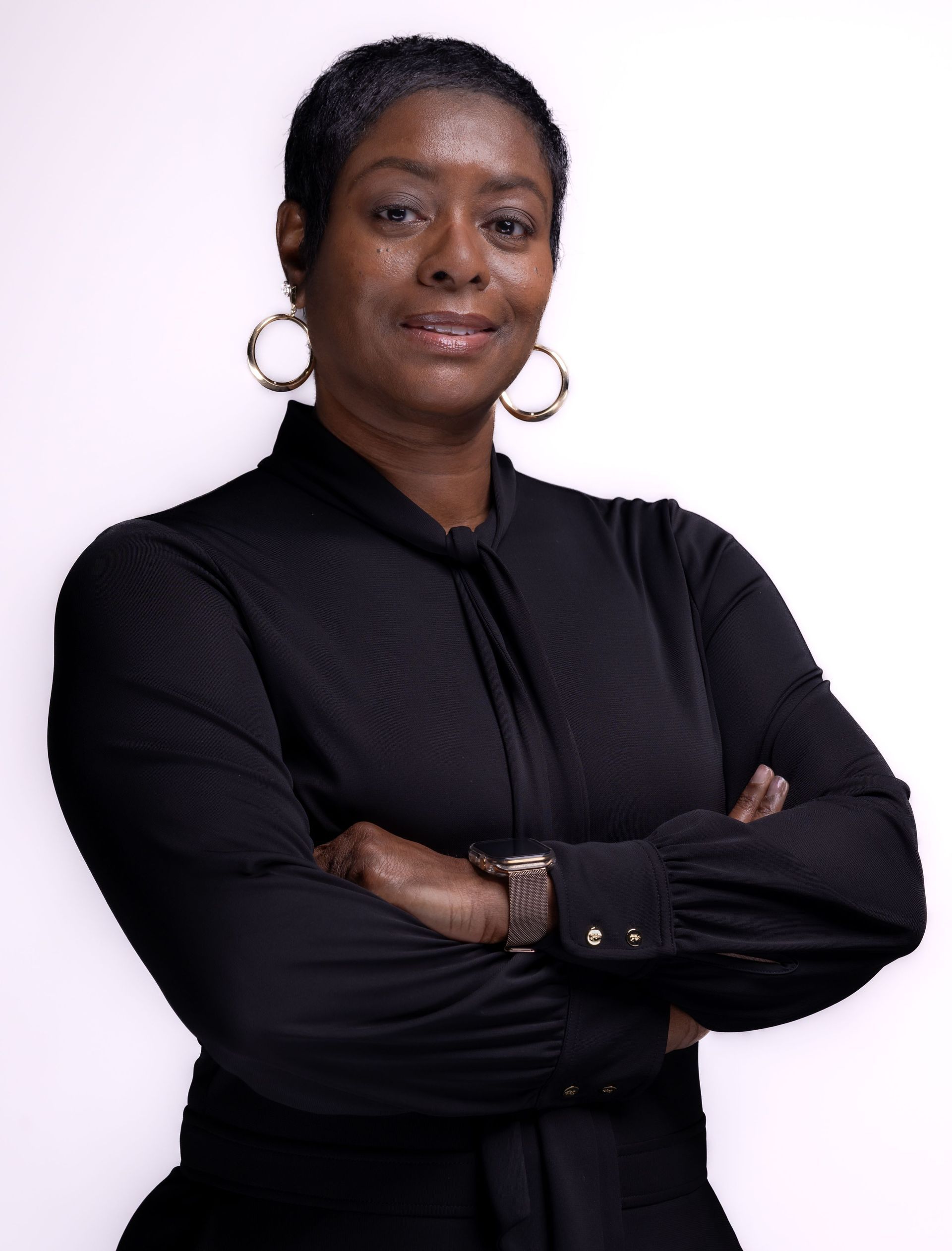 Person in a black top with arms crossed, posing against a white background.