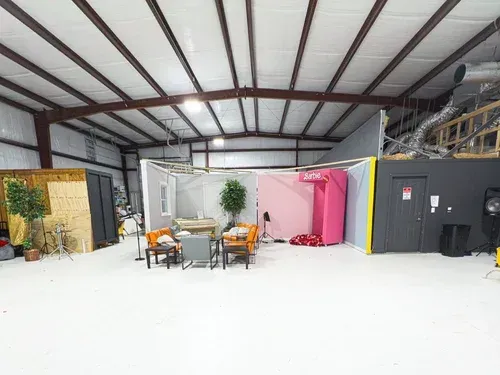 Indoor warehouse event space with lounge seating, colorful booths, and exposed metal beams