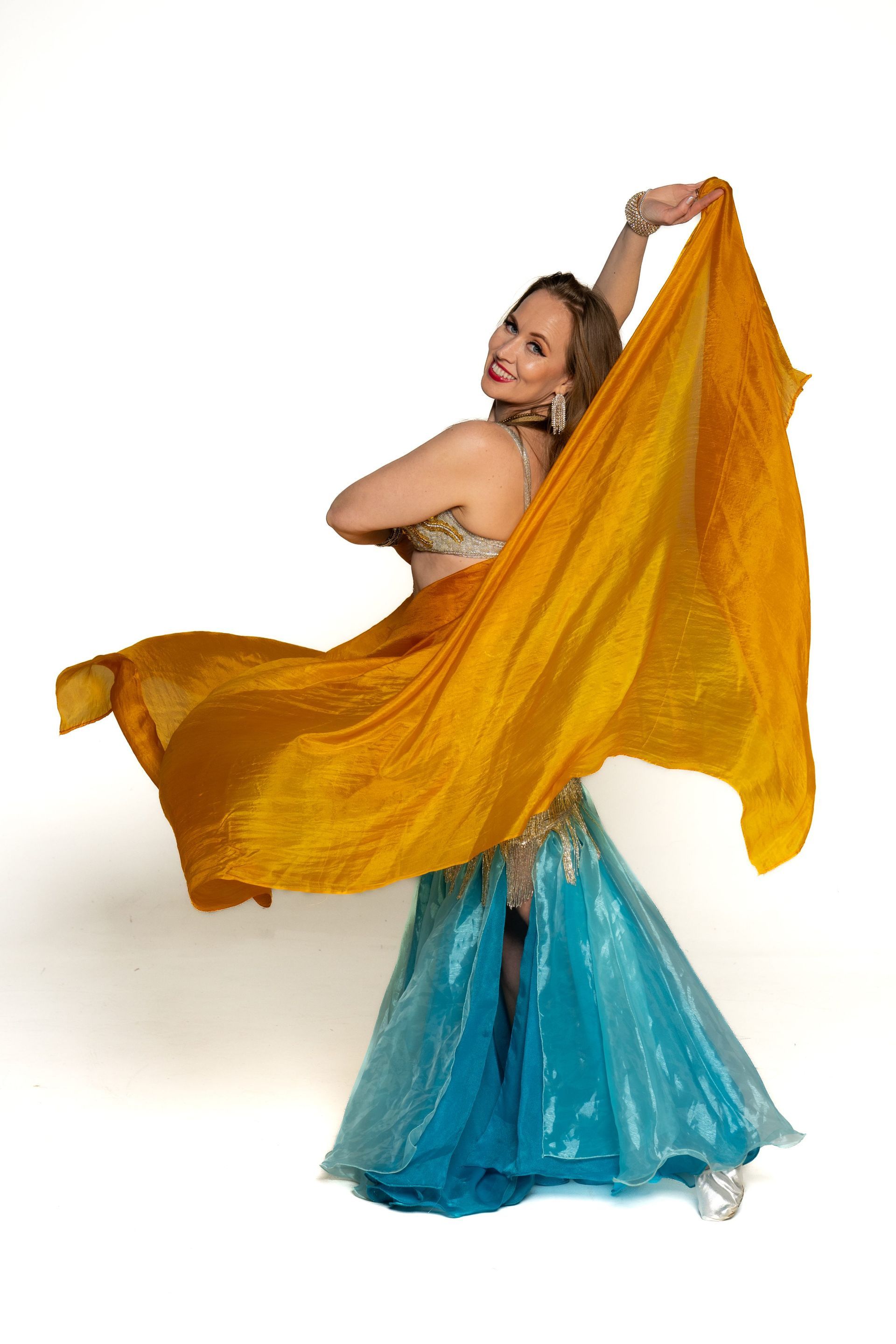 Dancer in a flowing yellow veil and blue skirt, mid-twirl against a white background