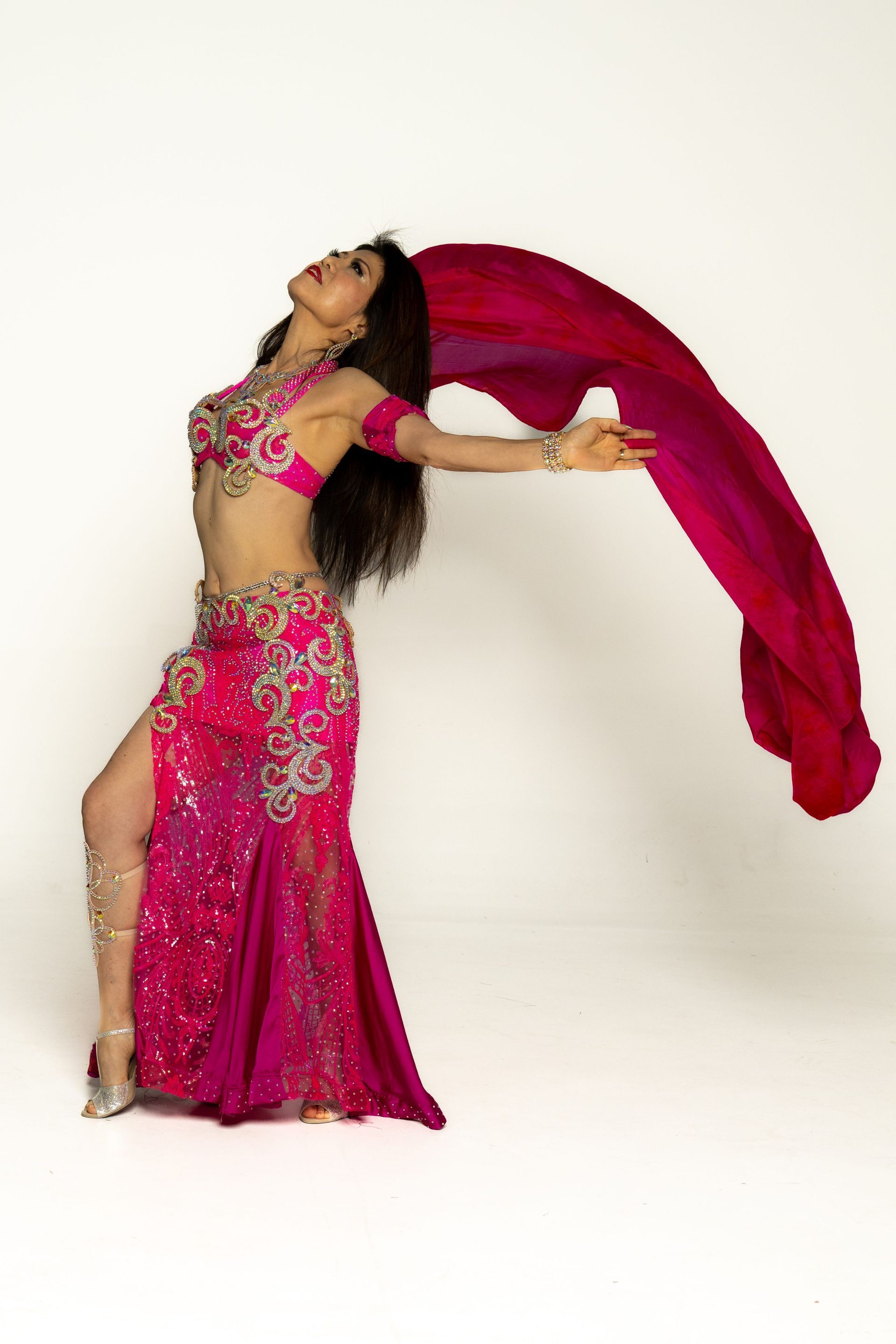 Dancer in a pink costume twirls a long red scarf against a plain white background