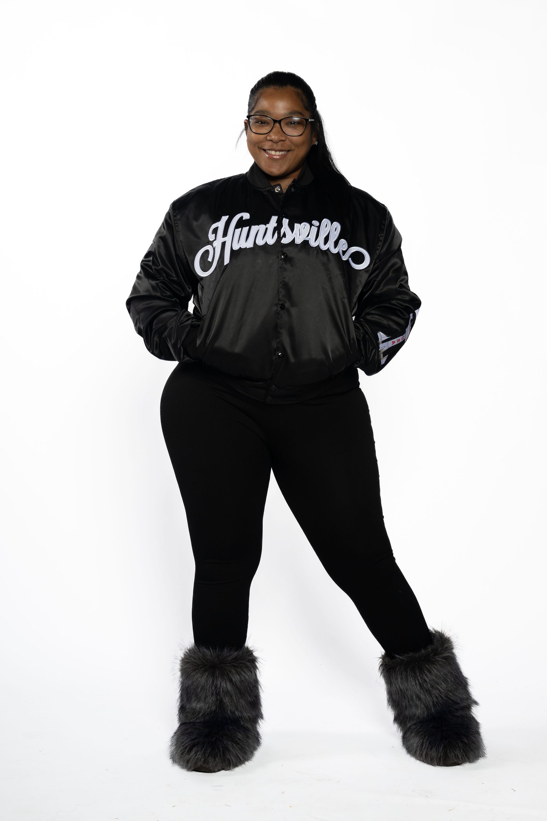Person in black hoodie and leggings standing against a white background, wearing furry boots.