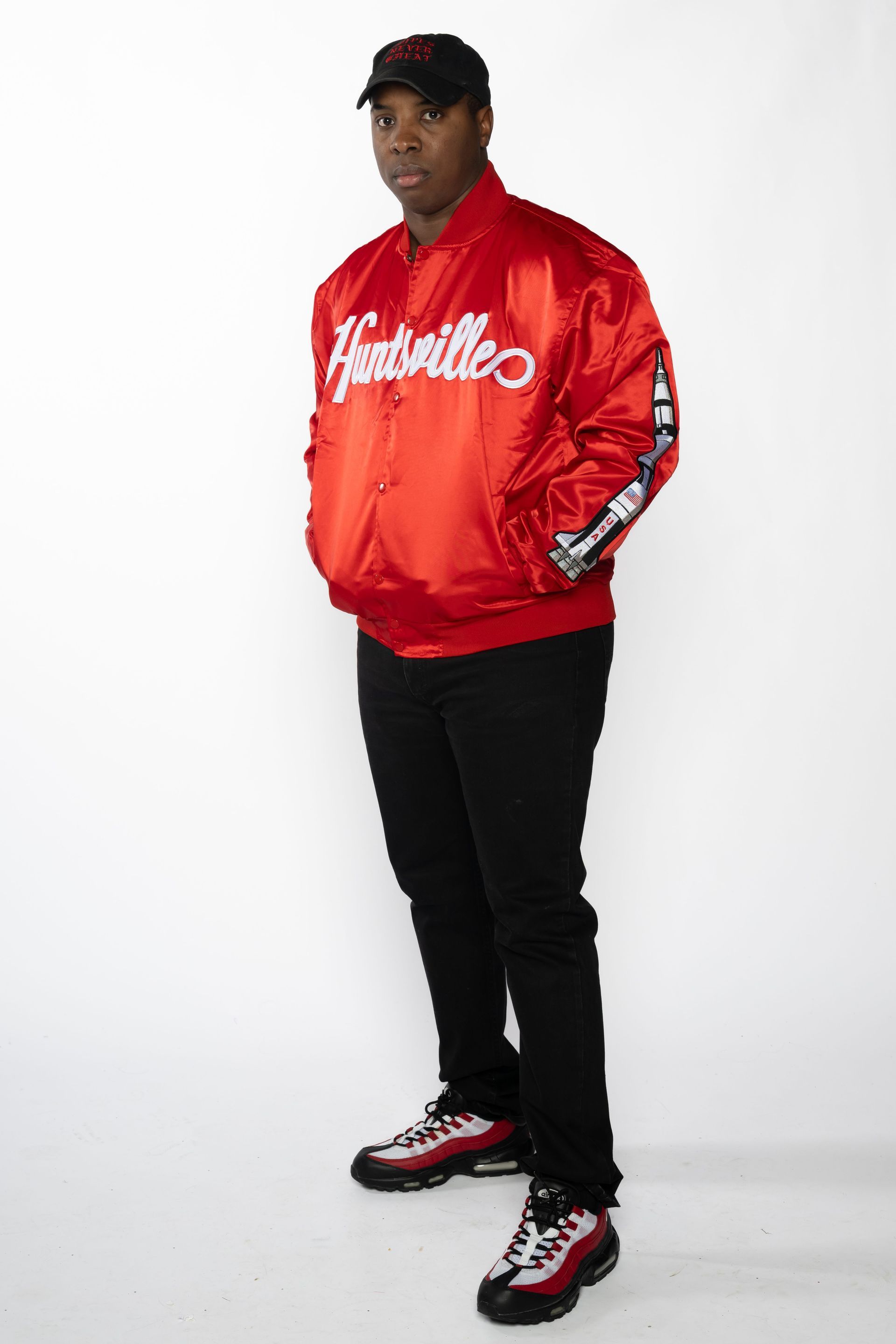 Person in a red jacket, black pants, and red-black sneakers posing against a white background.