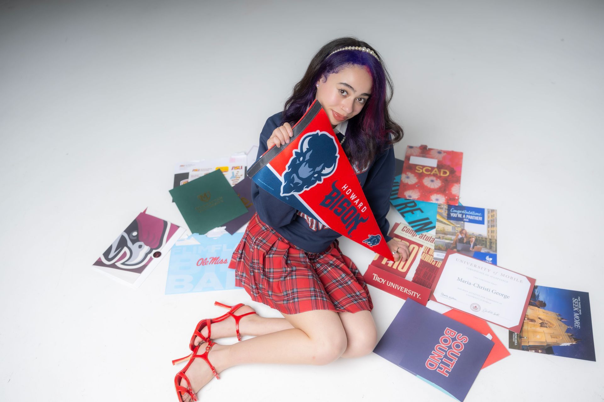 Woman sitting on the floor surrounded by colorful vinyl records and sleeves, holding a red record cover
