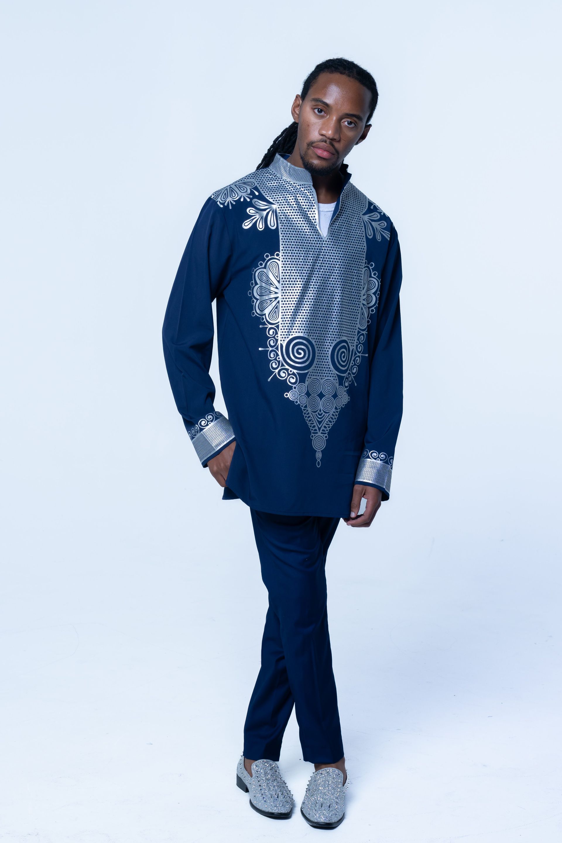 Person posing in a navy embroidered outfit against a light studio background.