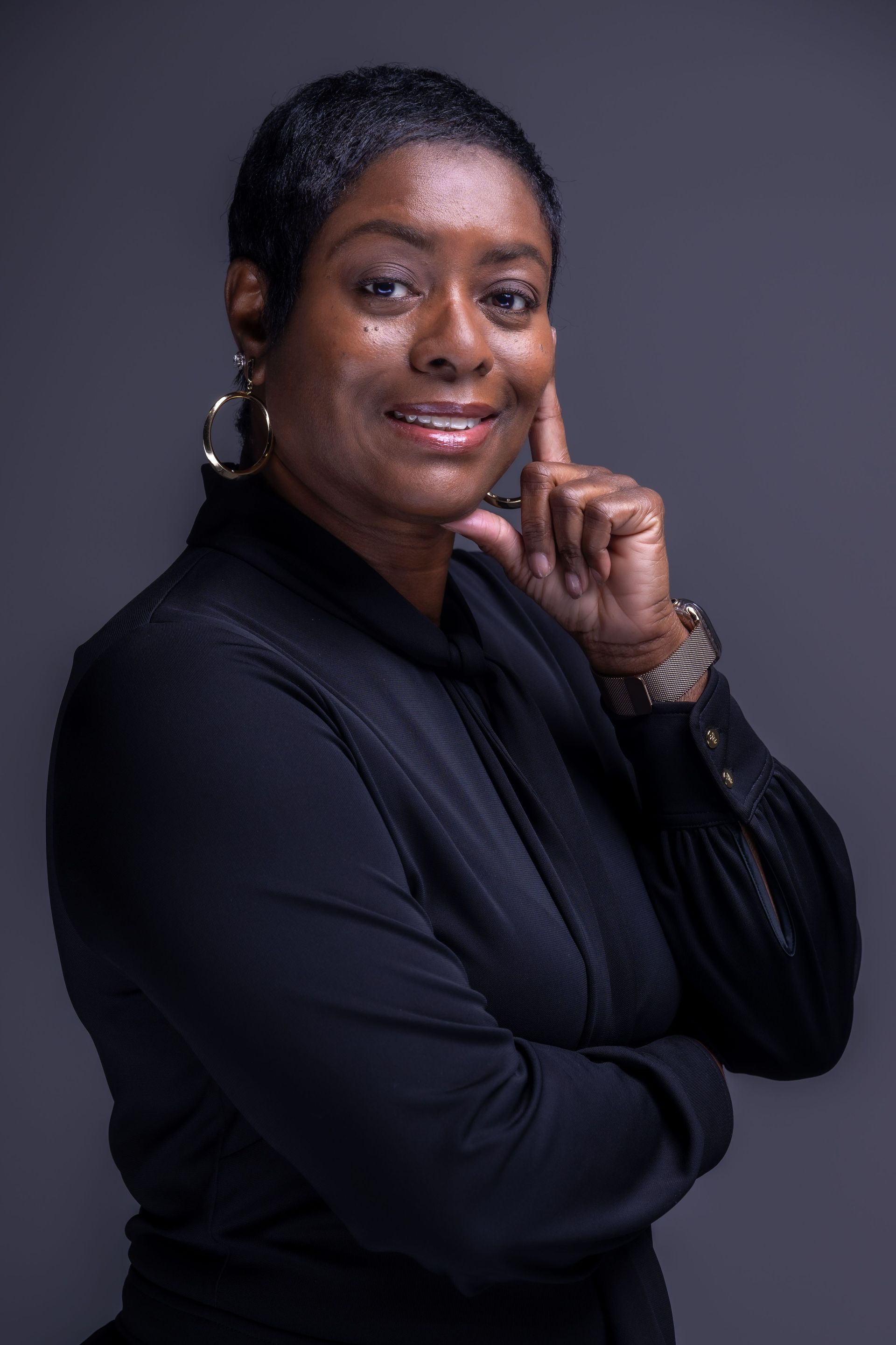 Portrait of a smiling person in a black top against a dark gray background
