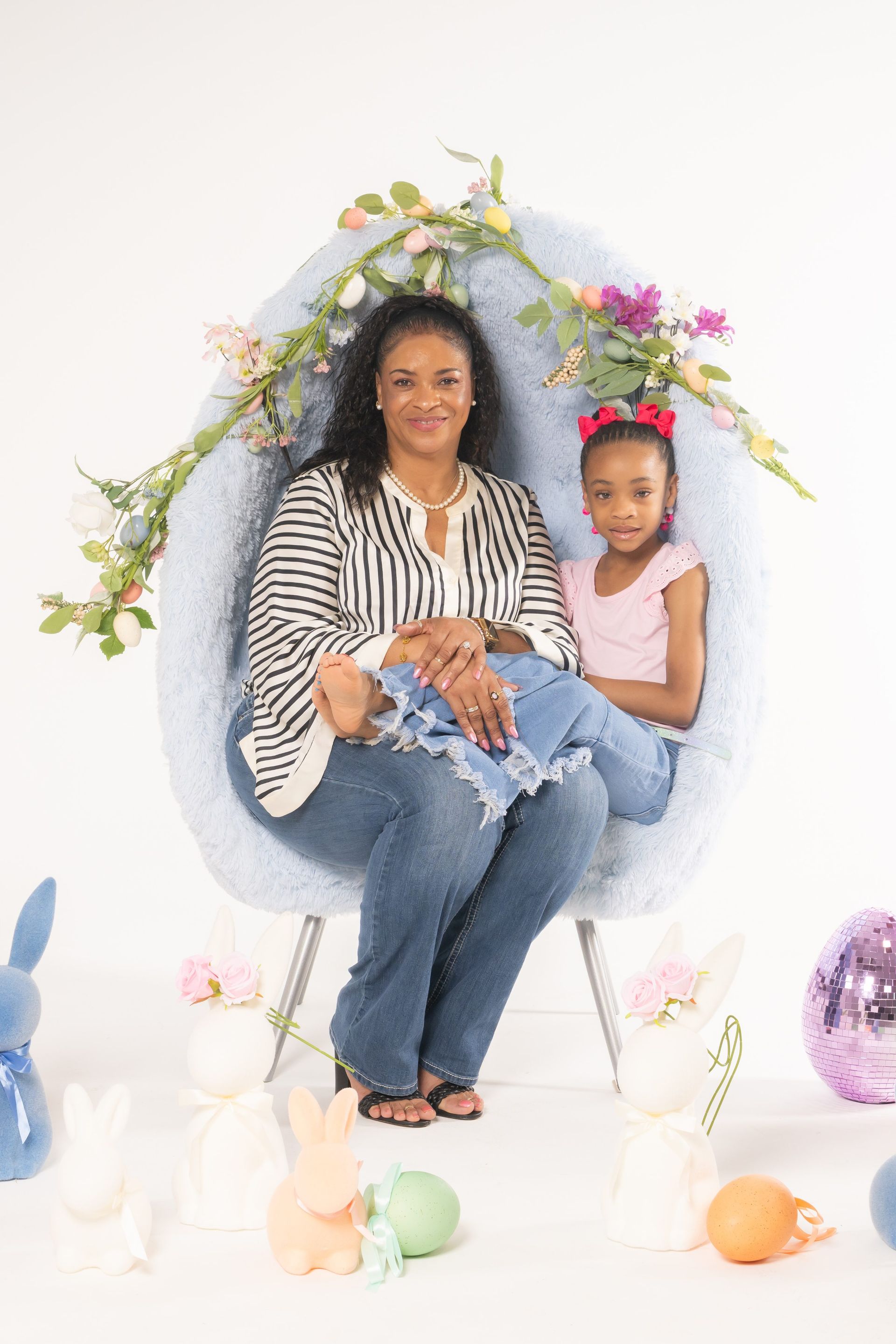Woman and child seated in an oval floral nest, surrounded by pastel bunnies and Easter eggs