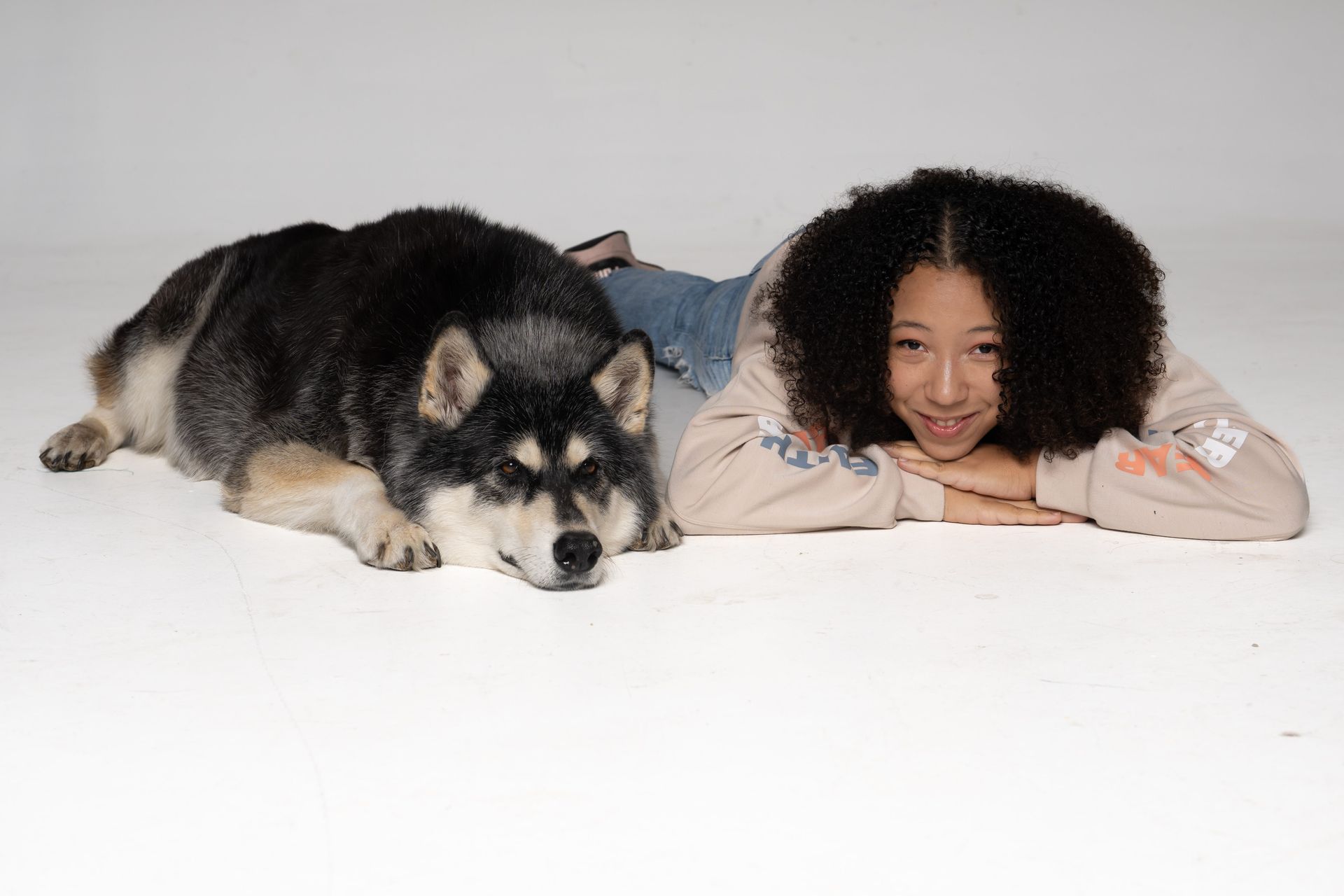 Woman lying next to a sleeping husky on a white background