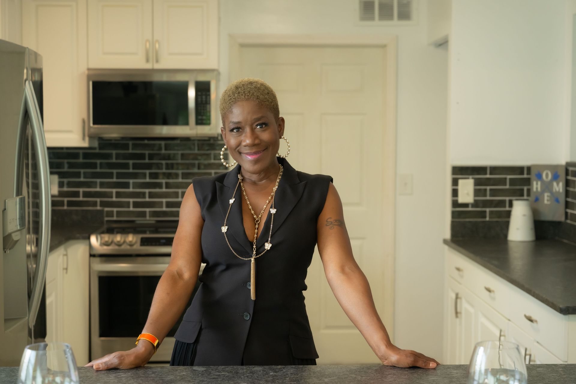 Woman standing in a bright kitchen, smiling behind a countertop.