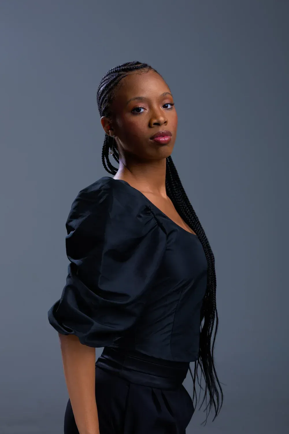 Portrait of a woman in a black blouse against a plain gray background