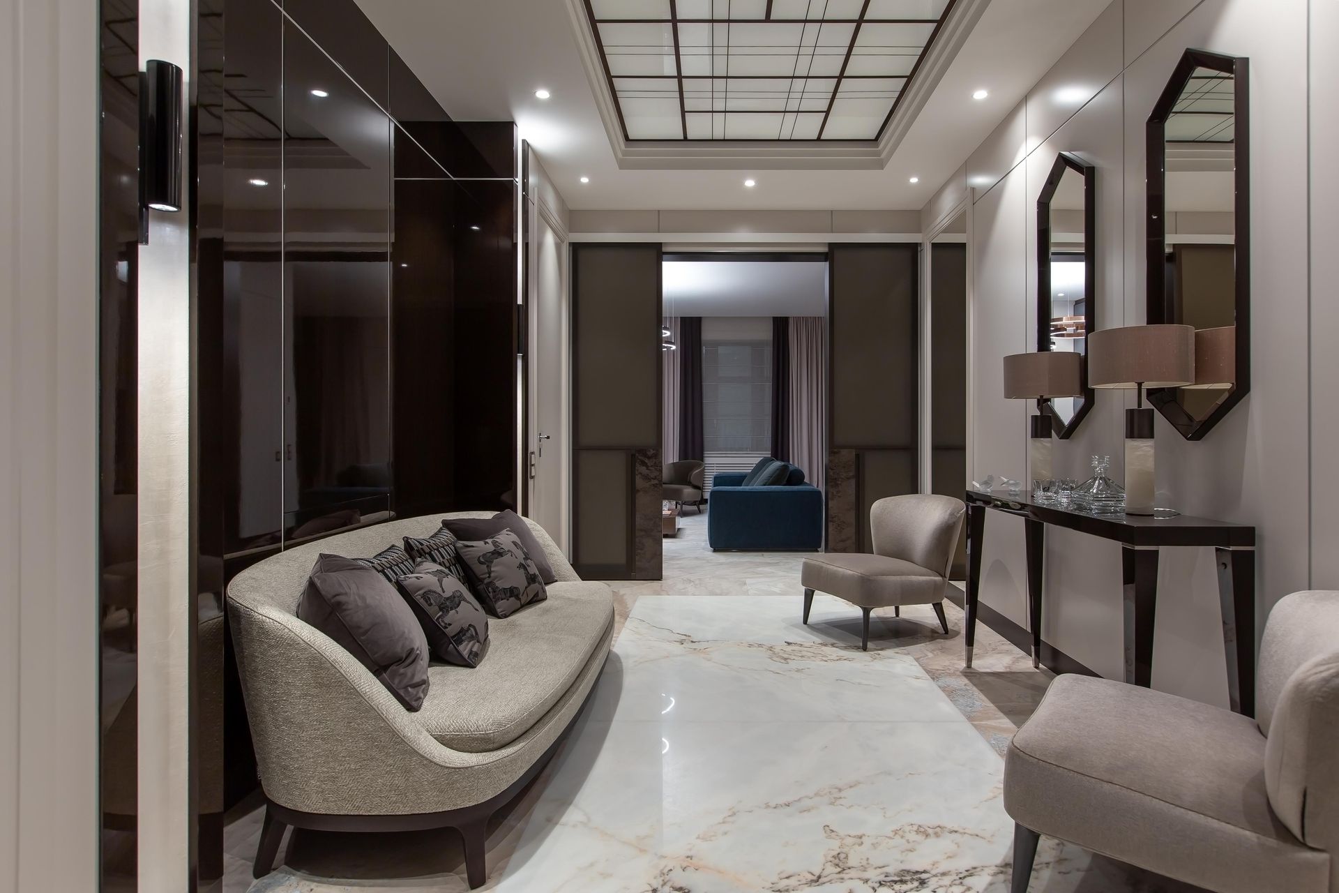 Elegant hallway with sofa, chairs, mirrors, and marble flooring.