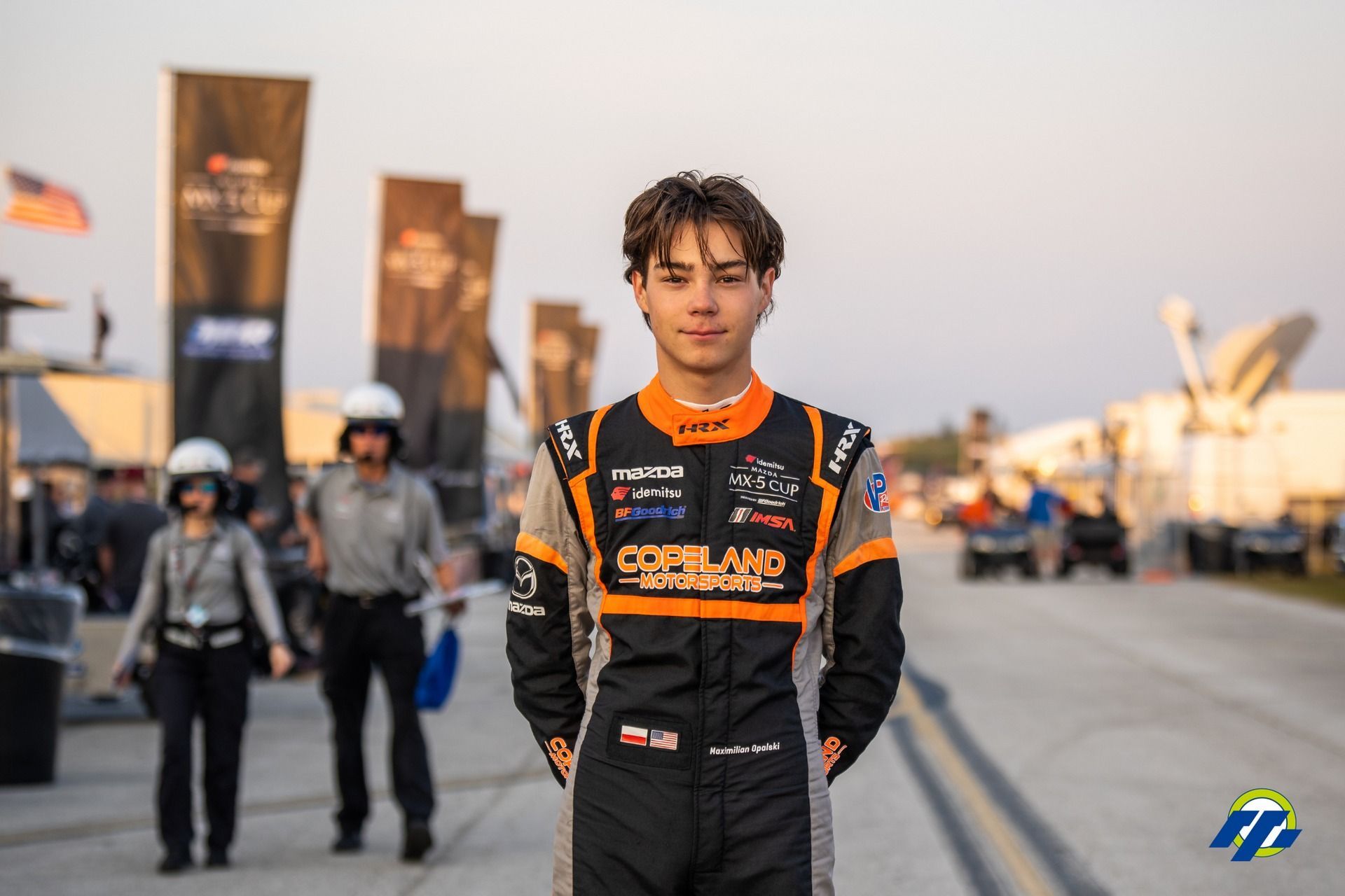 Max Opalski in a race suit is standing on a race track.