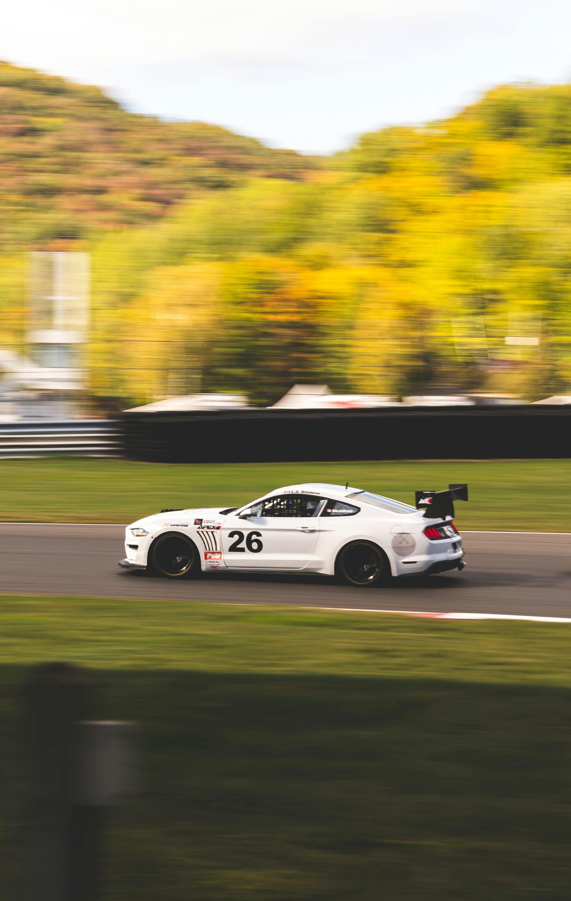 A white sports car is driving down a race track.