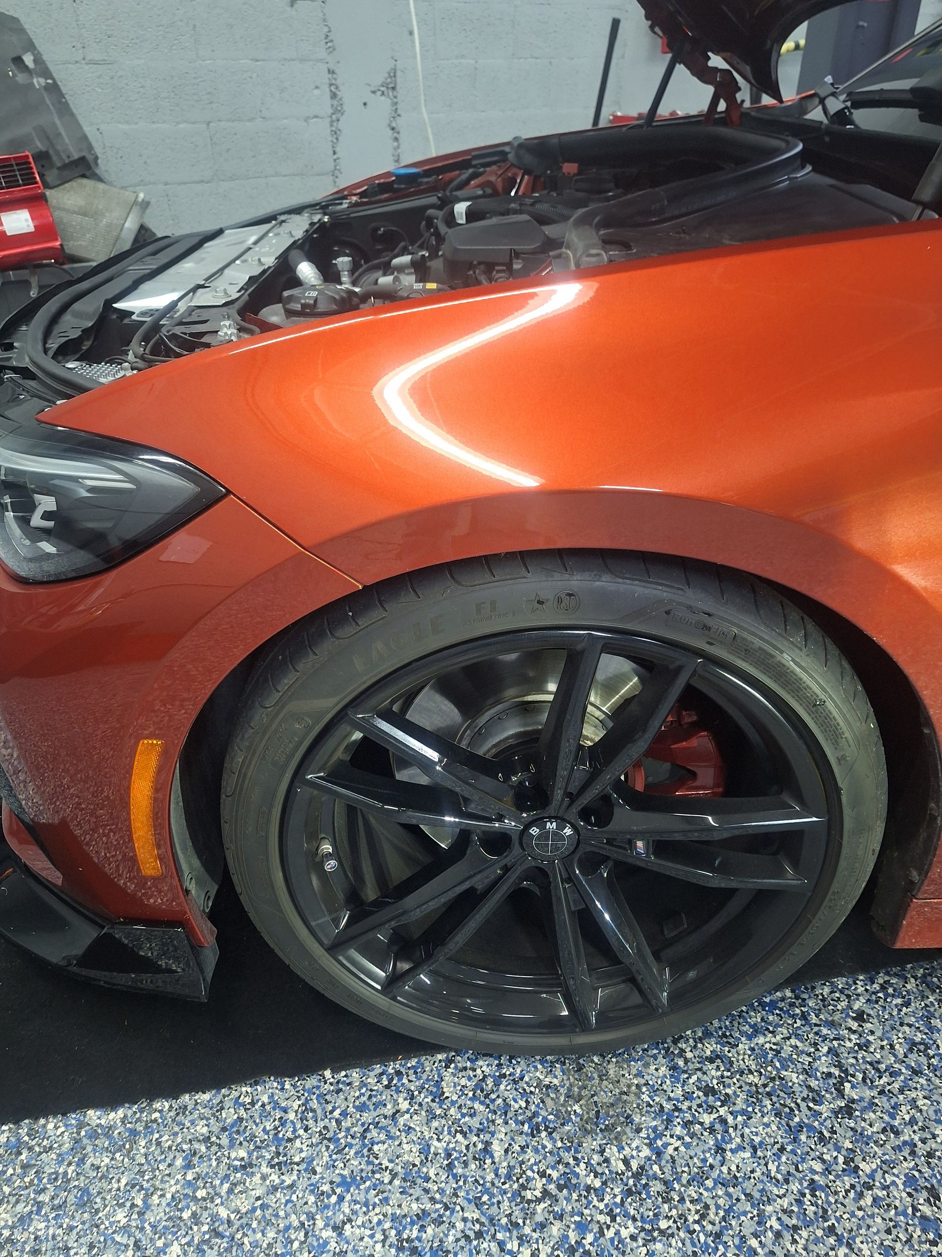 Orange sports car with black wheels parked in a garage, front fender and wheel visible | Temis Motorsports