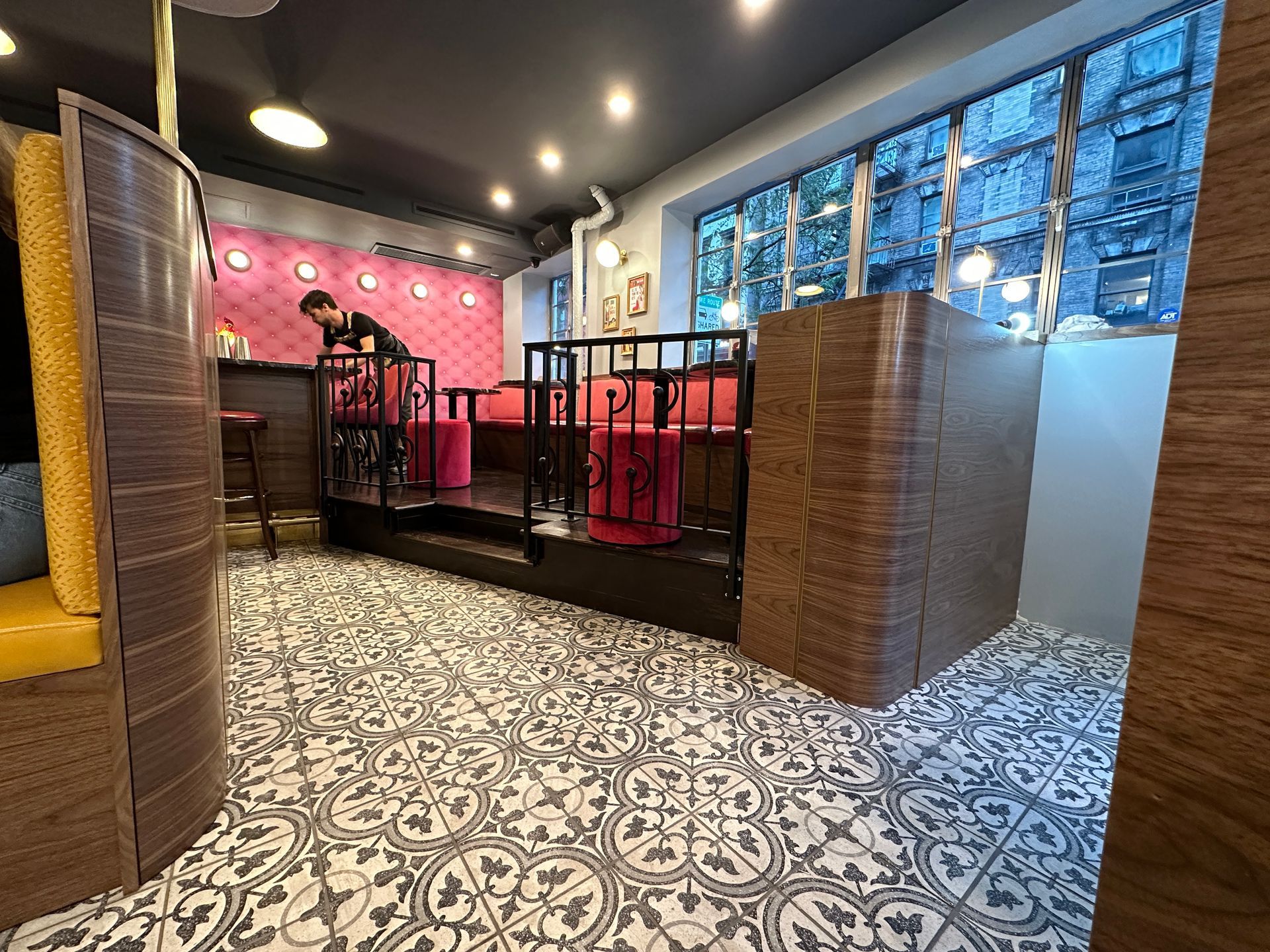 Modern restaurant interior with patterned tile floor, red booths, and large windows at night
