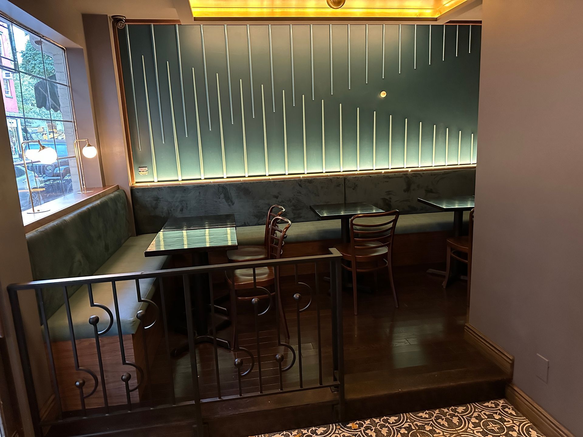 Cozy café booth with green banquette seating, wooden tables, and warm ambient lighting