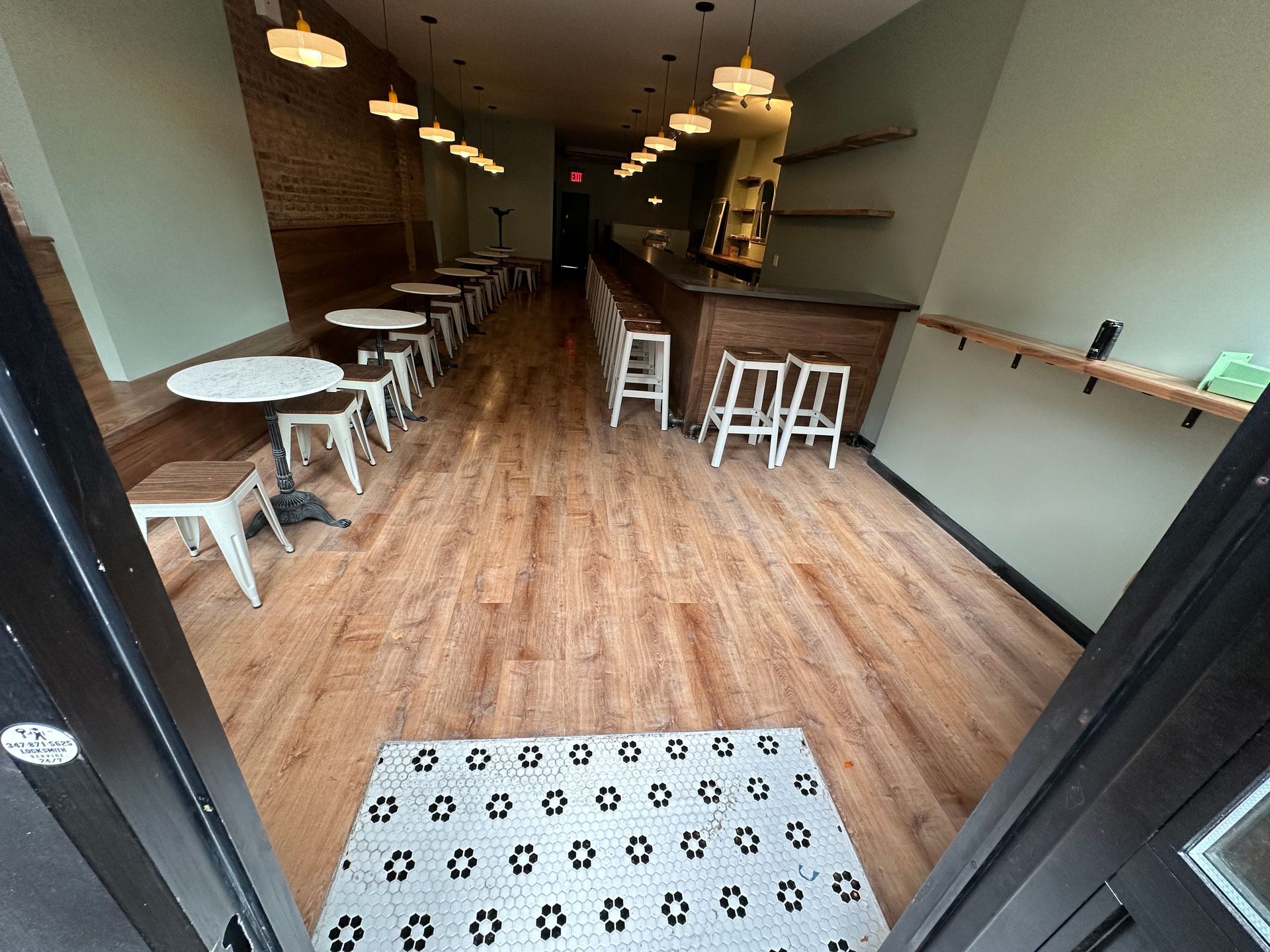 Empty café interior with wood floors, white stools, and a long counter.