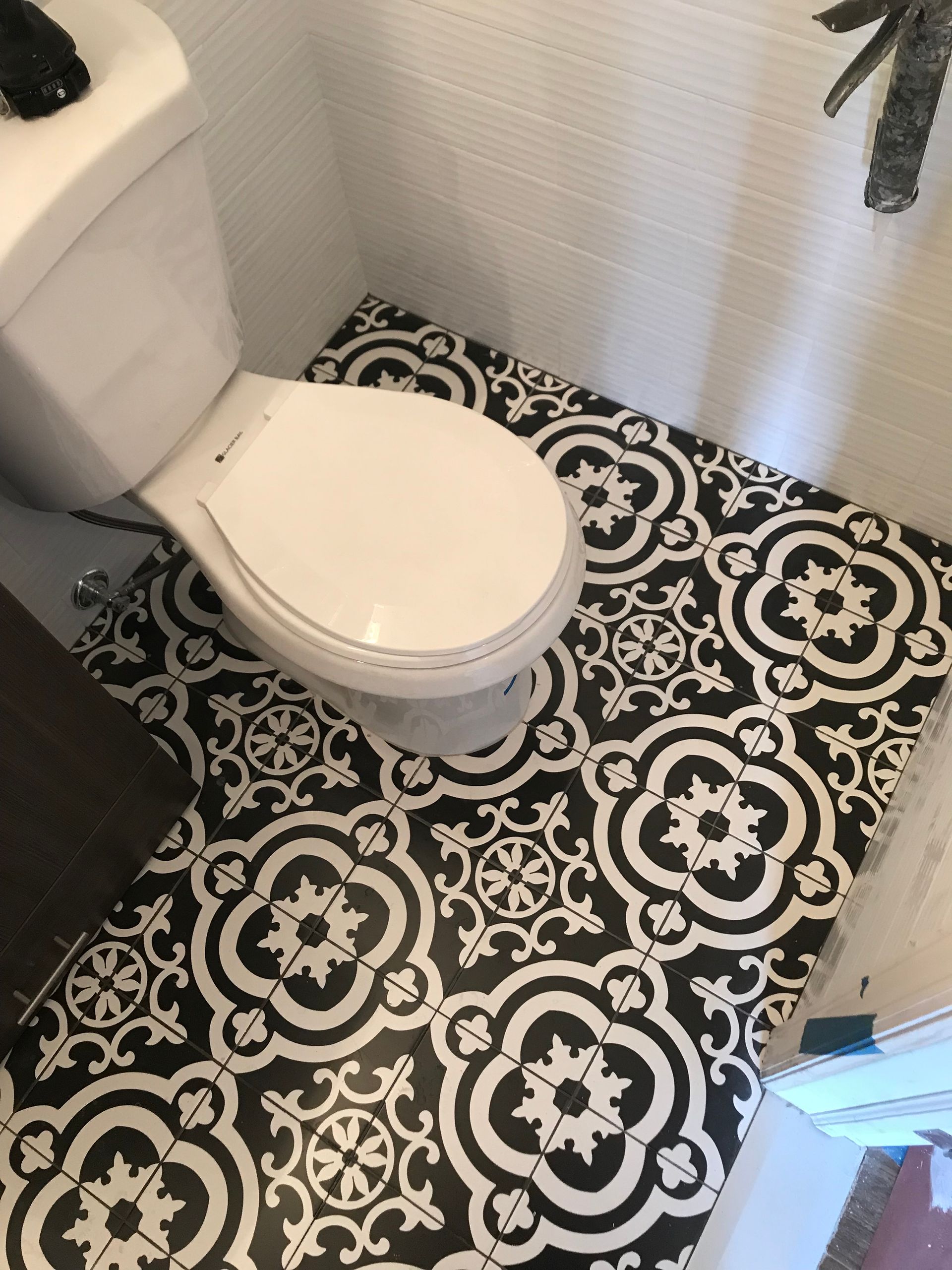 Small bathroom with white toilet and black-and-white patterned floor tile.