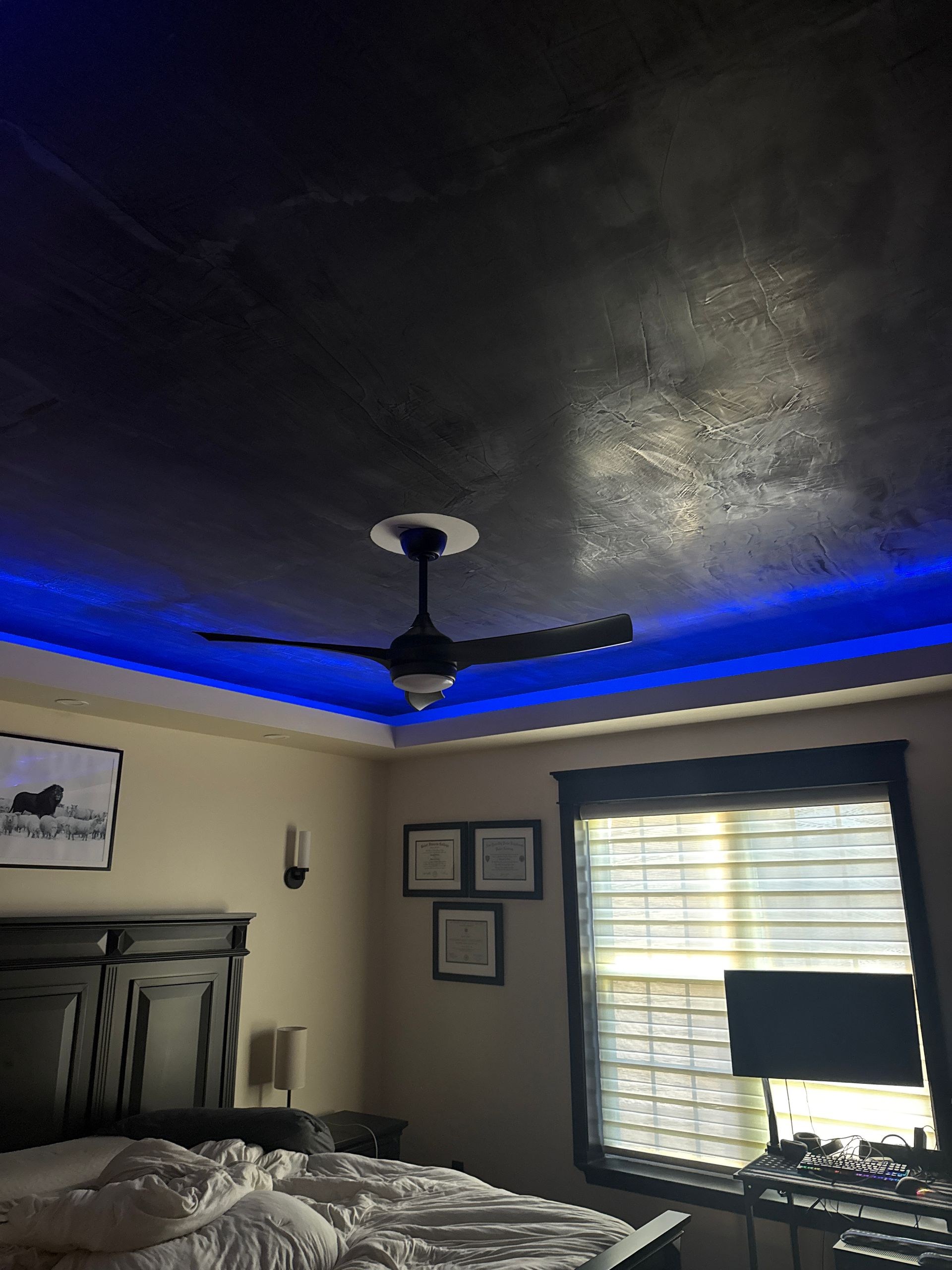 Bedroom with dark ceiling fan, blue LED ceiling lights, window blinds, and dresser under framed wall art