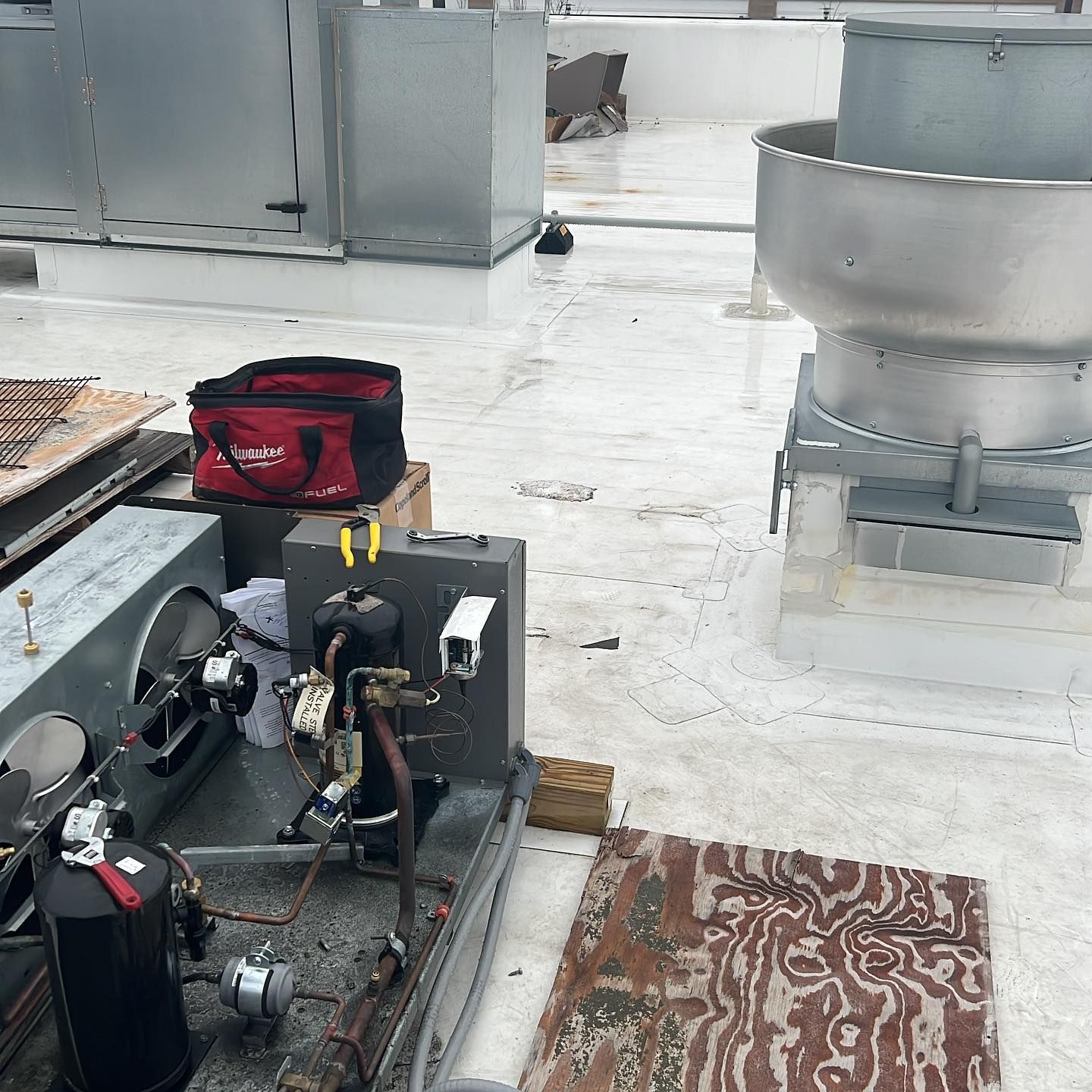 A red bag is sitting on top of a machine on a roof.