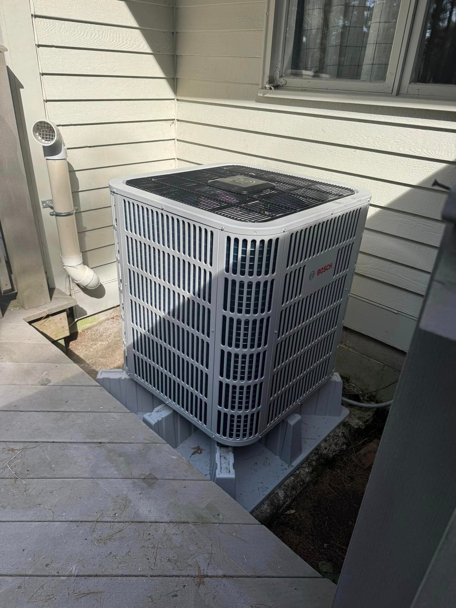 An air conditioner is sitting on the side of a house.