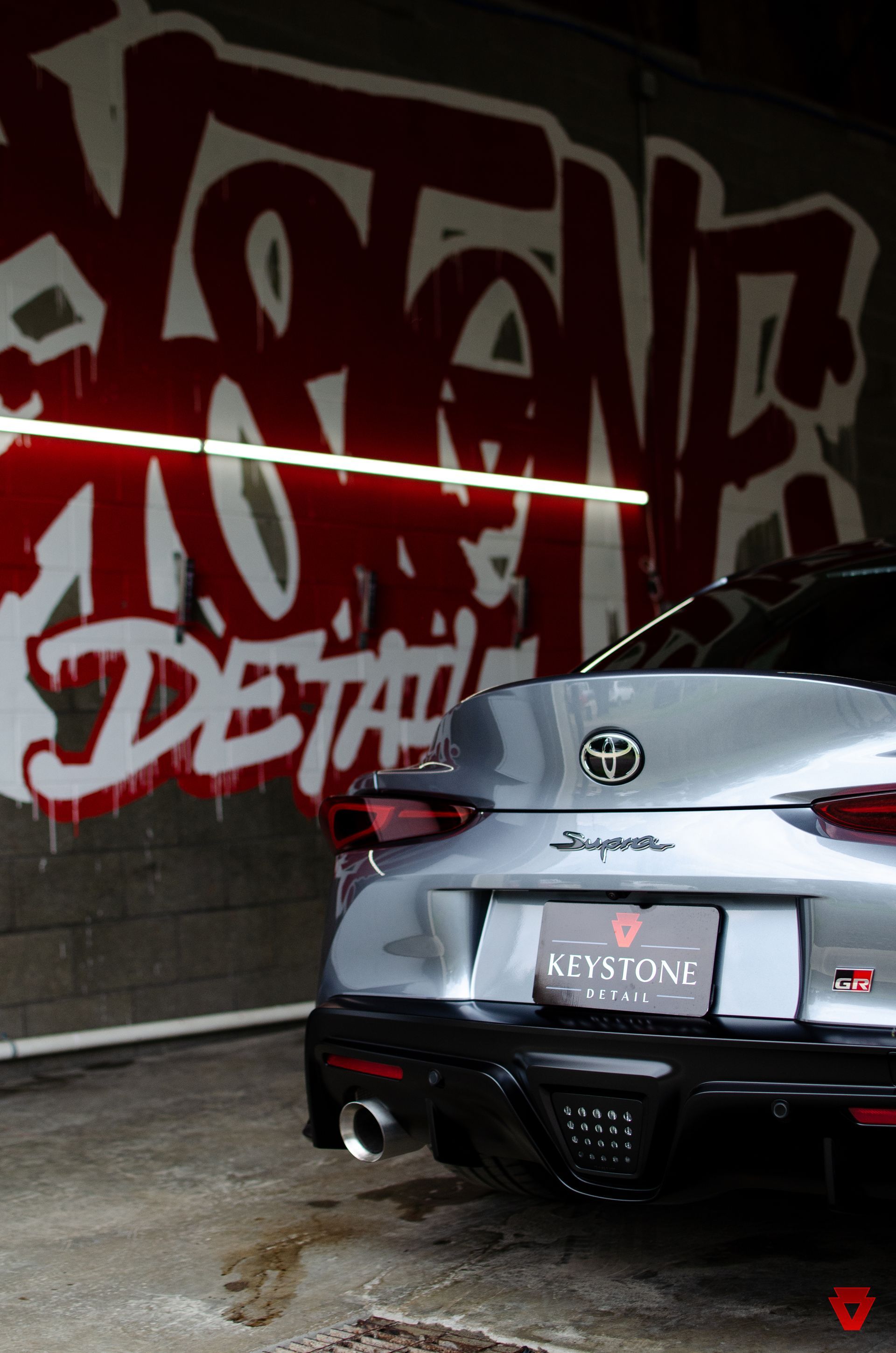 Silver Toyota SUV parked indoors in front of a red graffiti wall.