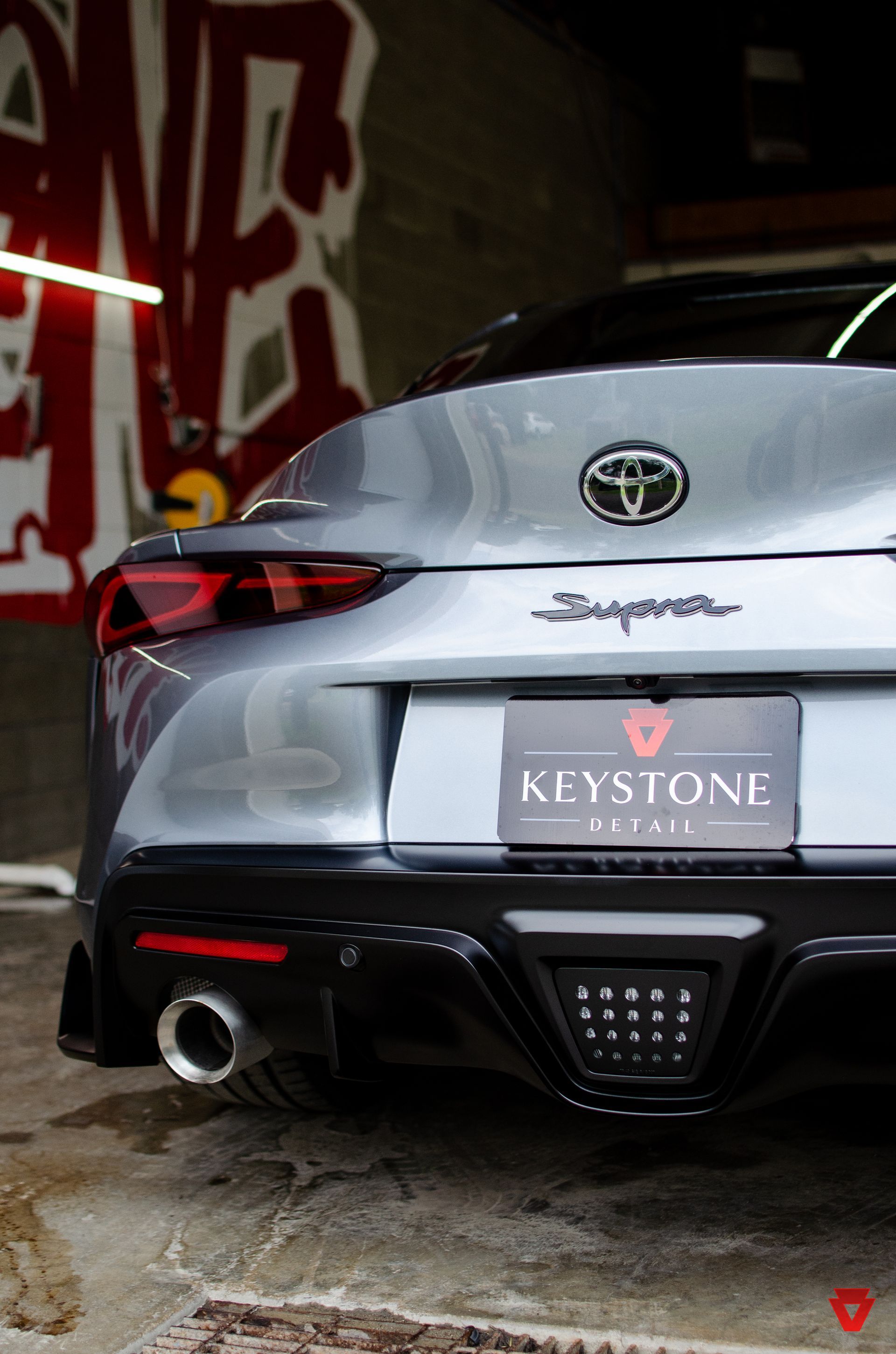 Rear view of a silver Toyota sedan parked in a graffiti-lined garage.