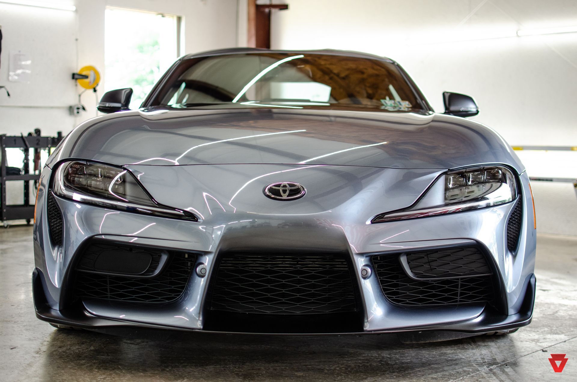 Front view of a silver sports car parked indoors in a garage or showroom