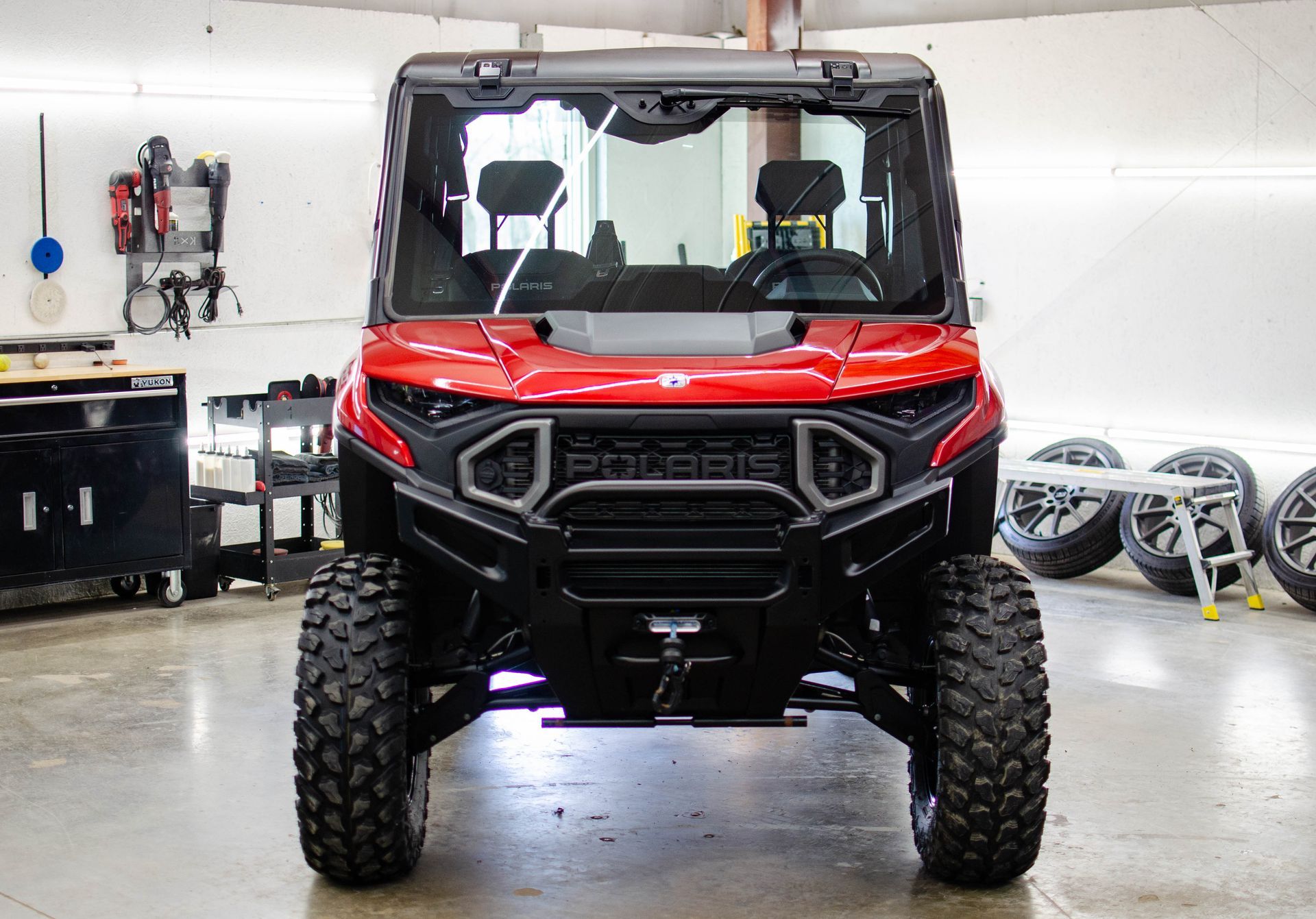 Red off-road utility vehicle in a garage, facing forward on a clean floor