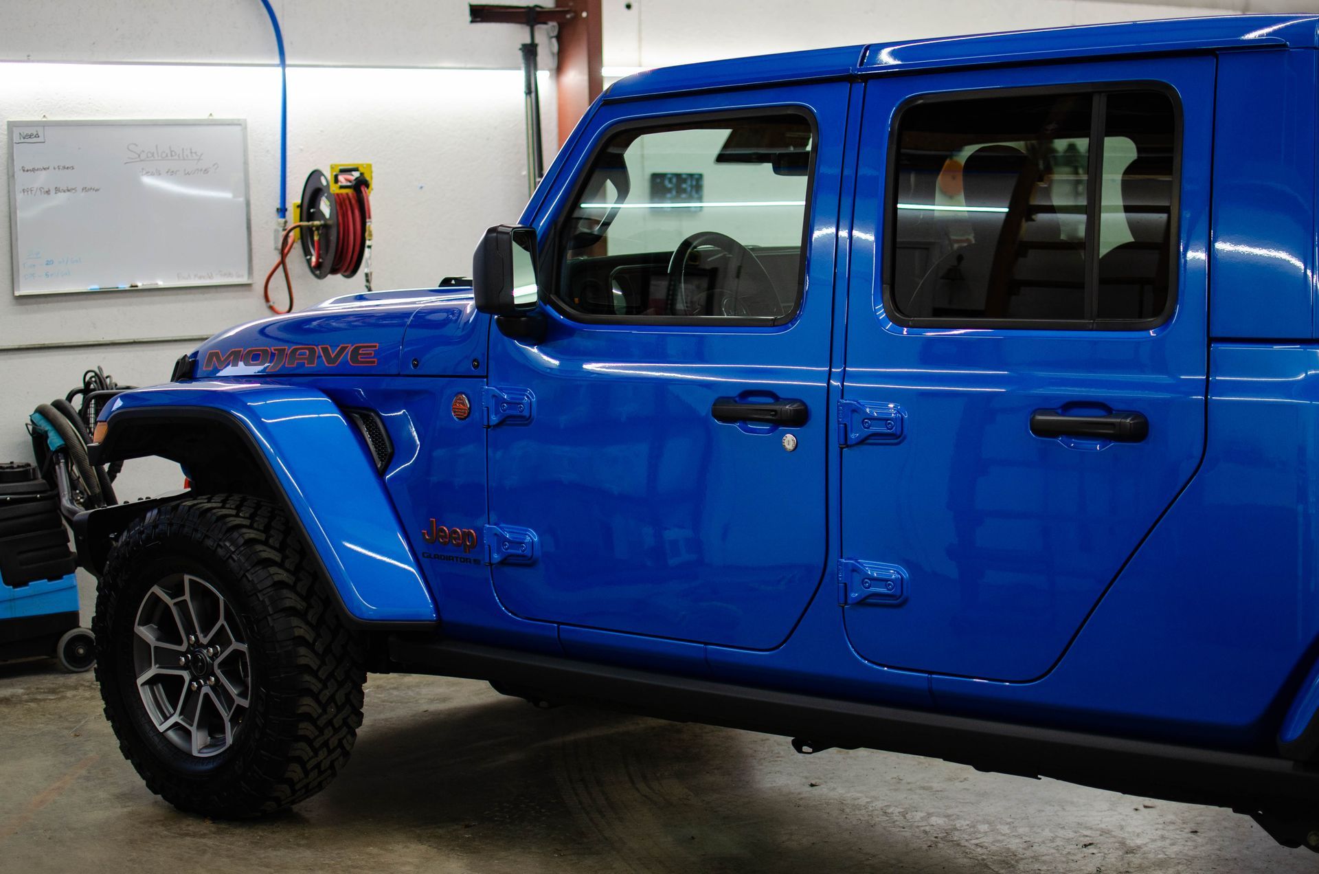 Blue pickup truck parked in a garage, viewed from the side.