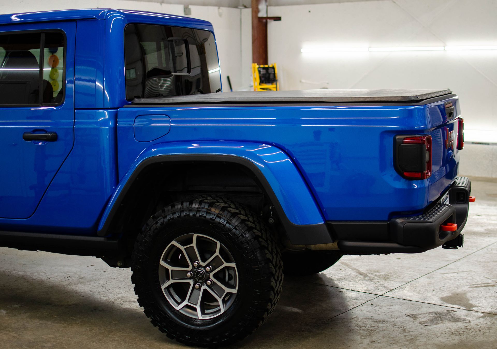 Blue pickup truck parked indoors, side view with off-road tires and black trim
