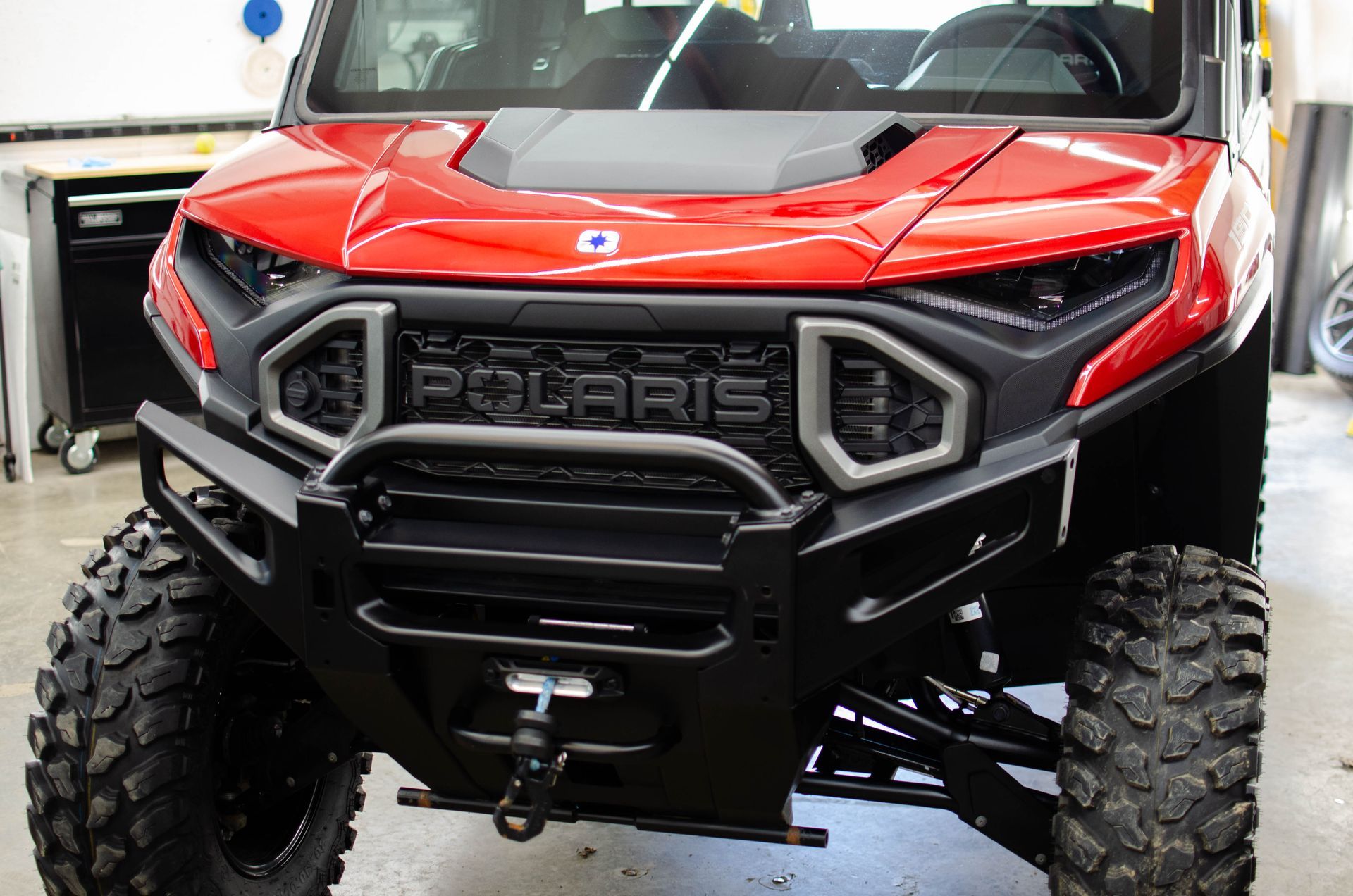 Red Polaris off-road vehicle with large tires, front view, in a showroom