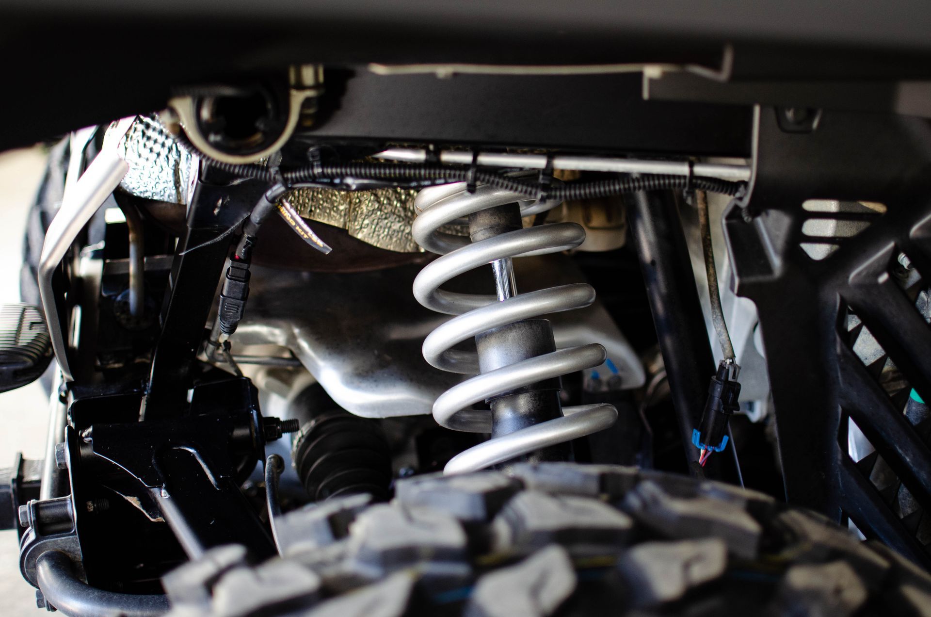 Close-up of a vehicle suspension with a silver coil spring under the chassis