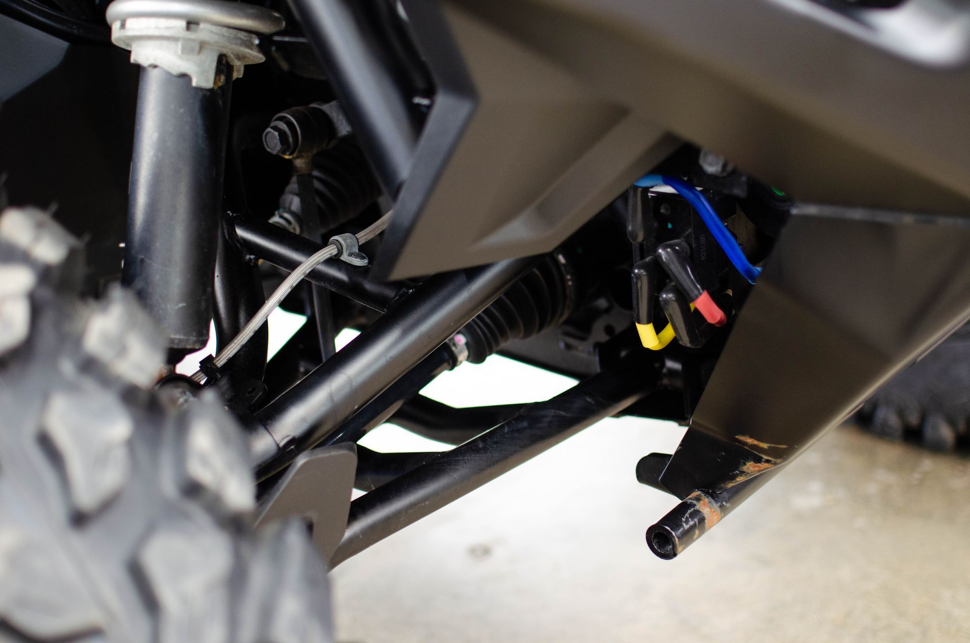Close-up of ATV undercarriage with suspension, wiring, and off-road tire visible