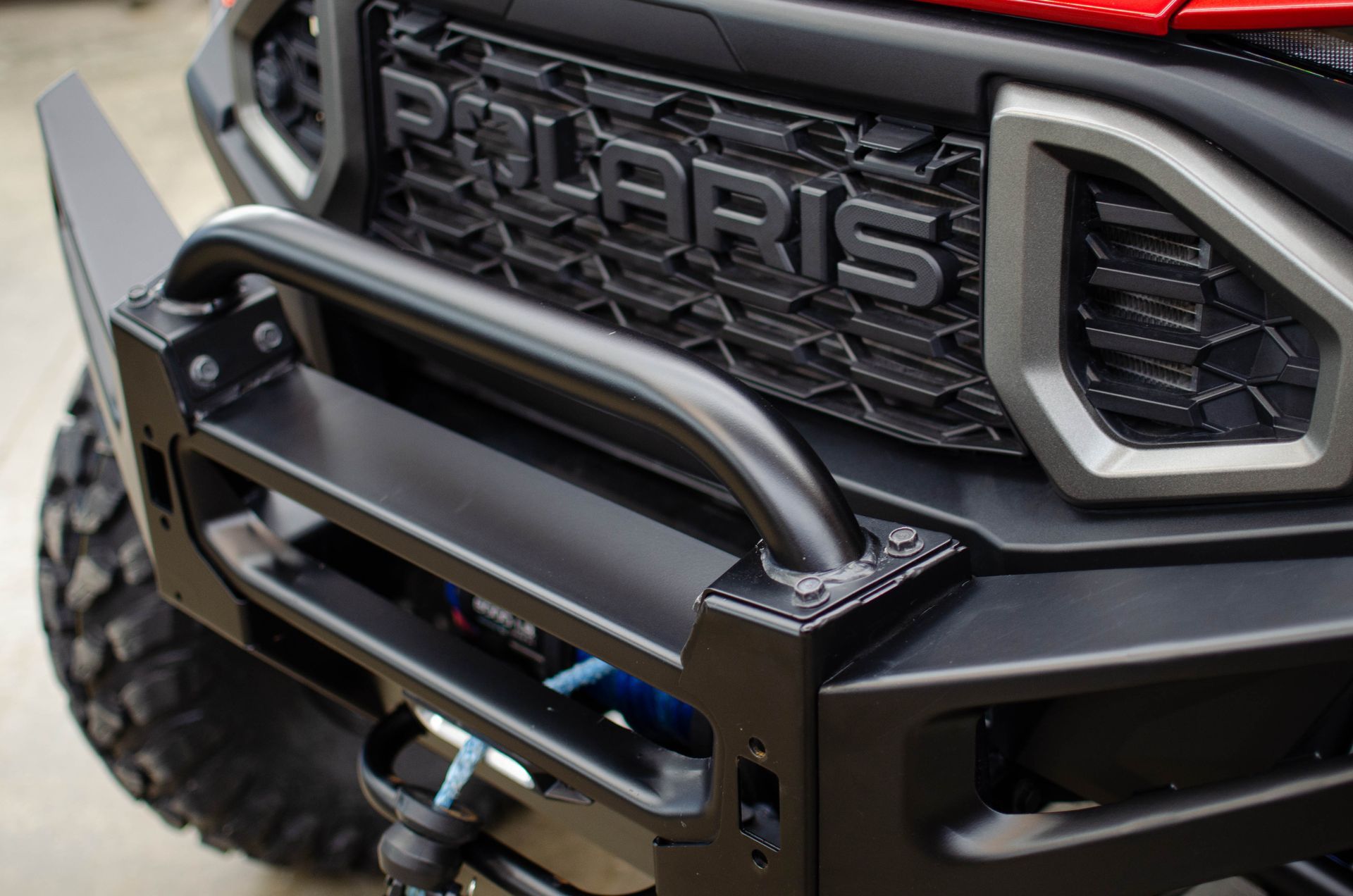 Close-up of a black Polaris off-road vehicle front grille and bumper with winch