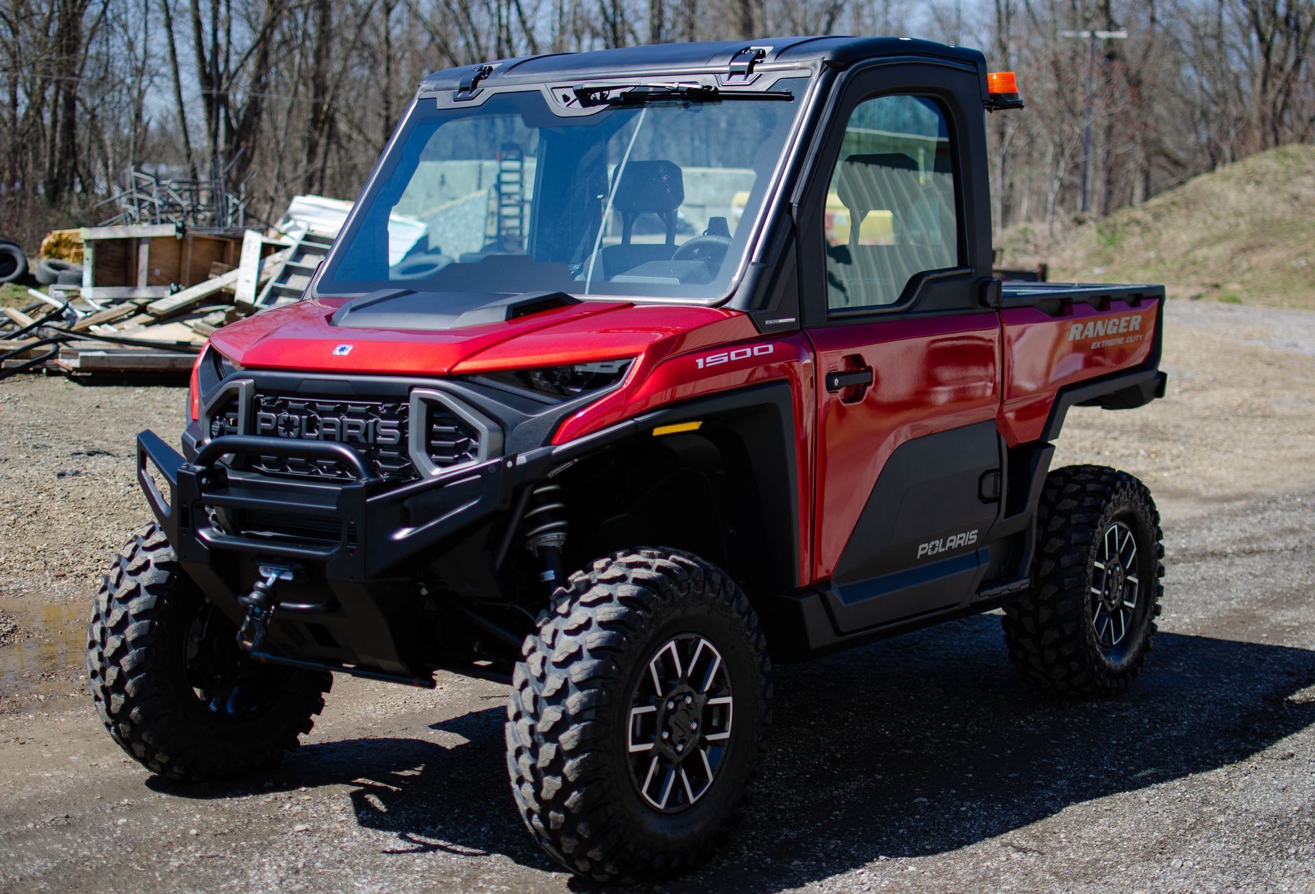Red-and-black off-road side-by-side utility vehicle parked on gravel outdoors