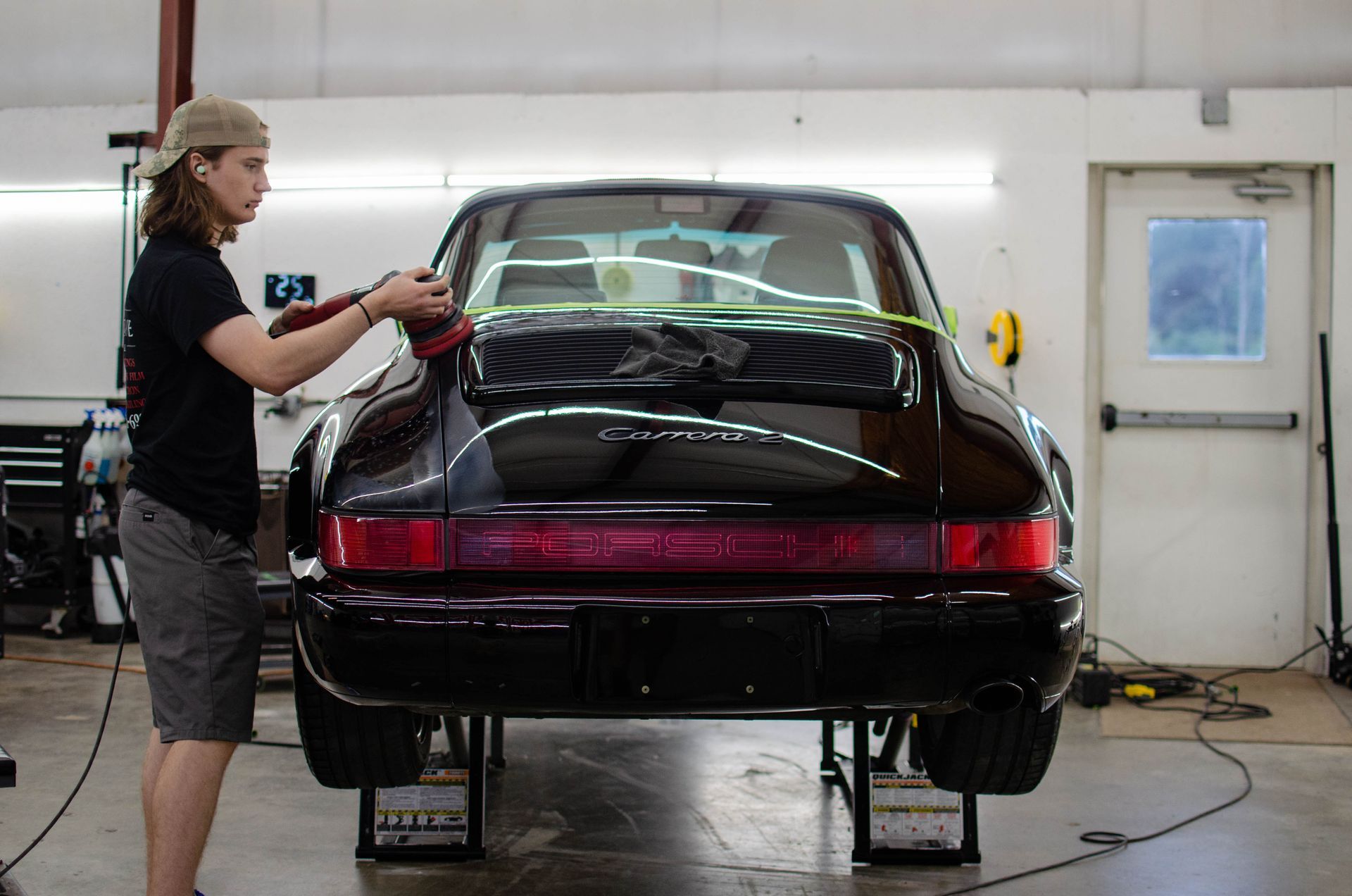 Person polishing a black sports car in a garage