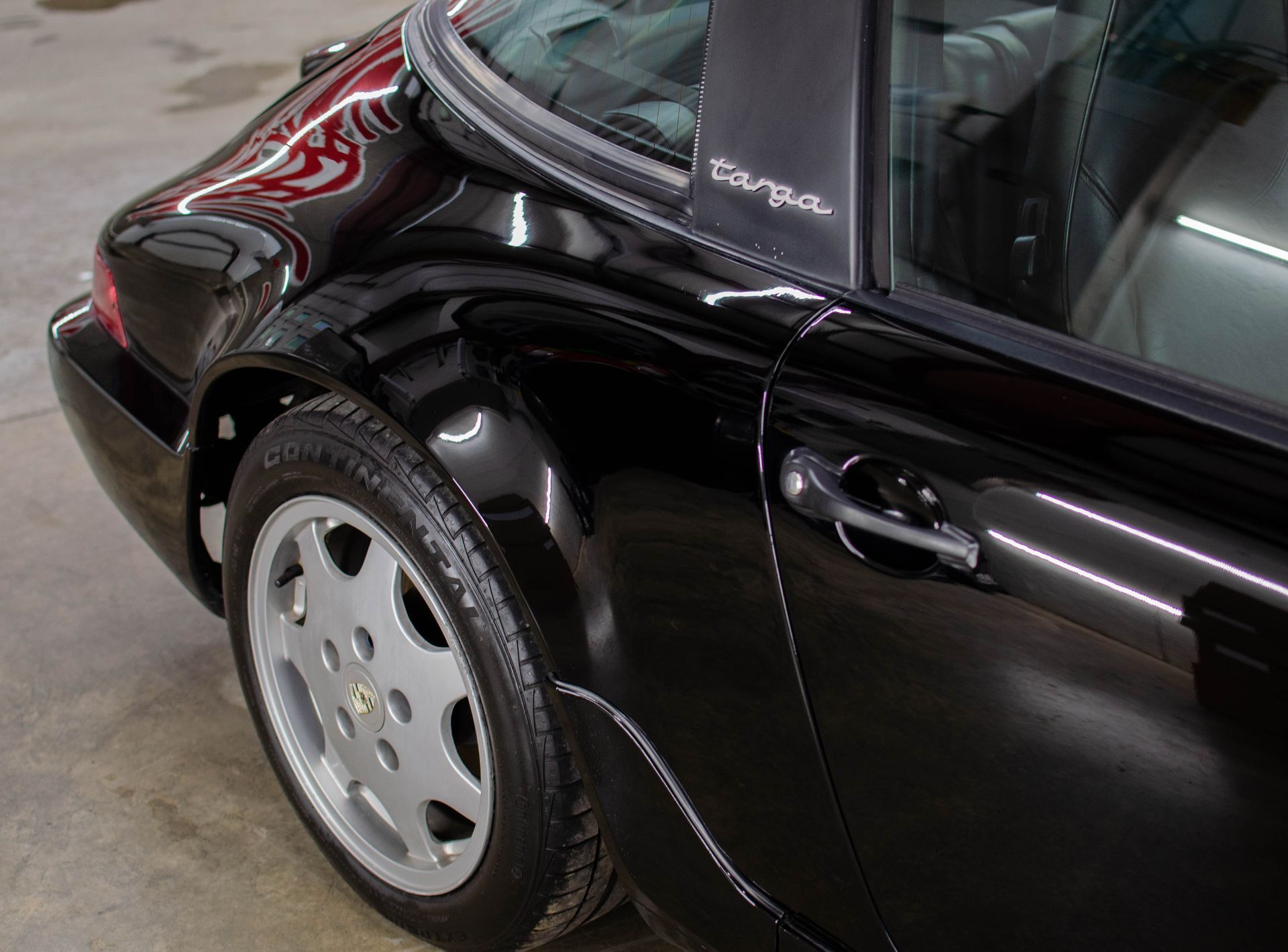 Close-up of a black car’s rear side and wheel in a garage
