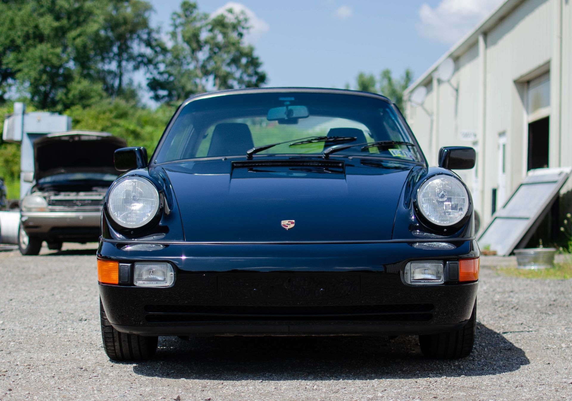 Front view of a dark blue Porsche 911 parked outdoors on a sunny day